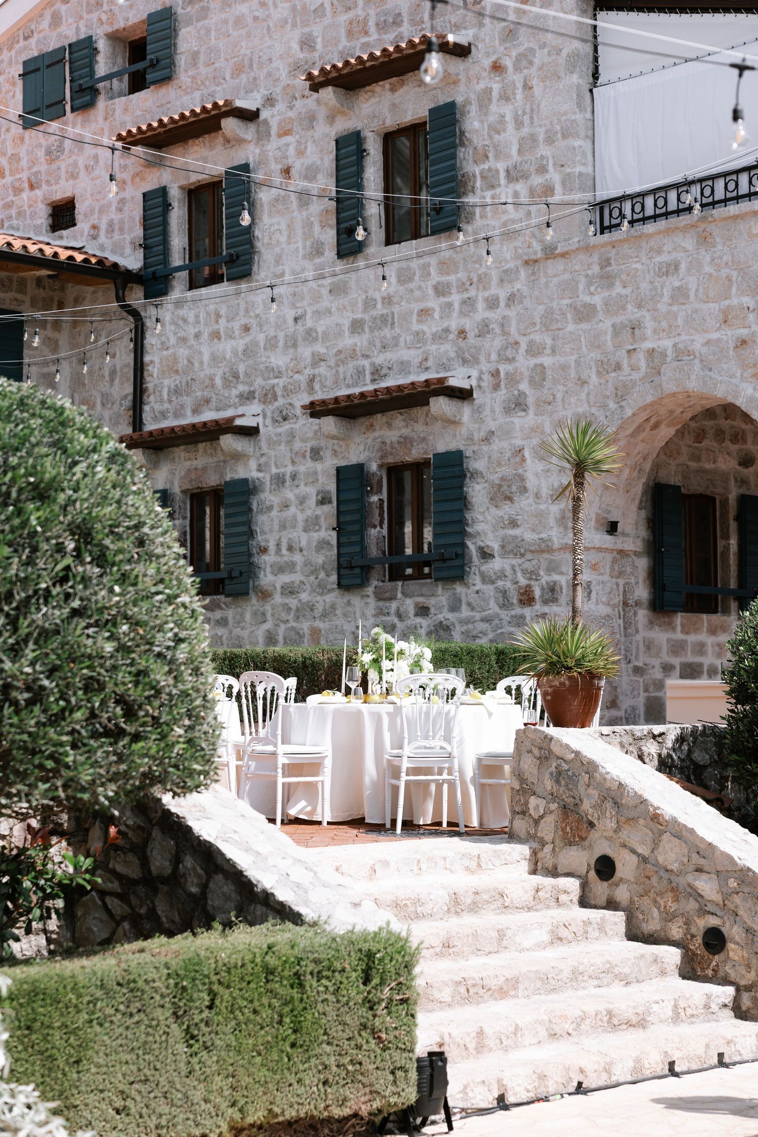 Stone building exterior with white chairs and steps creating a Mediterranean ambiance.
