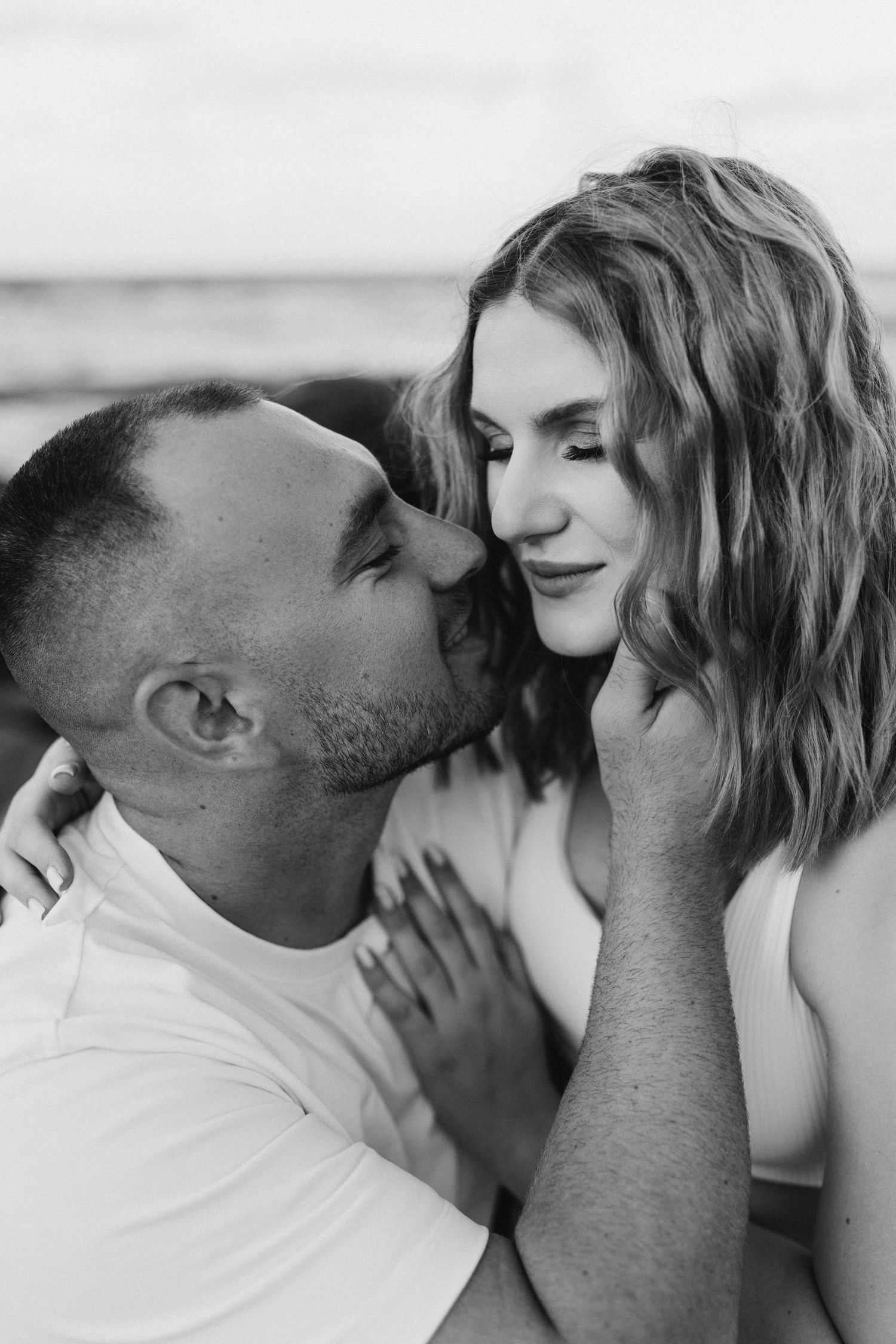 An intimate black and white portrait of a couple sharing a tender moment.