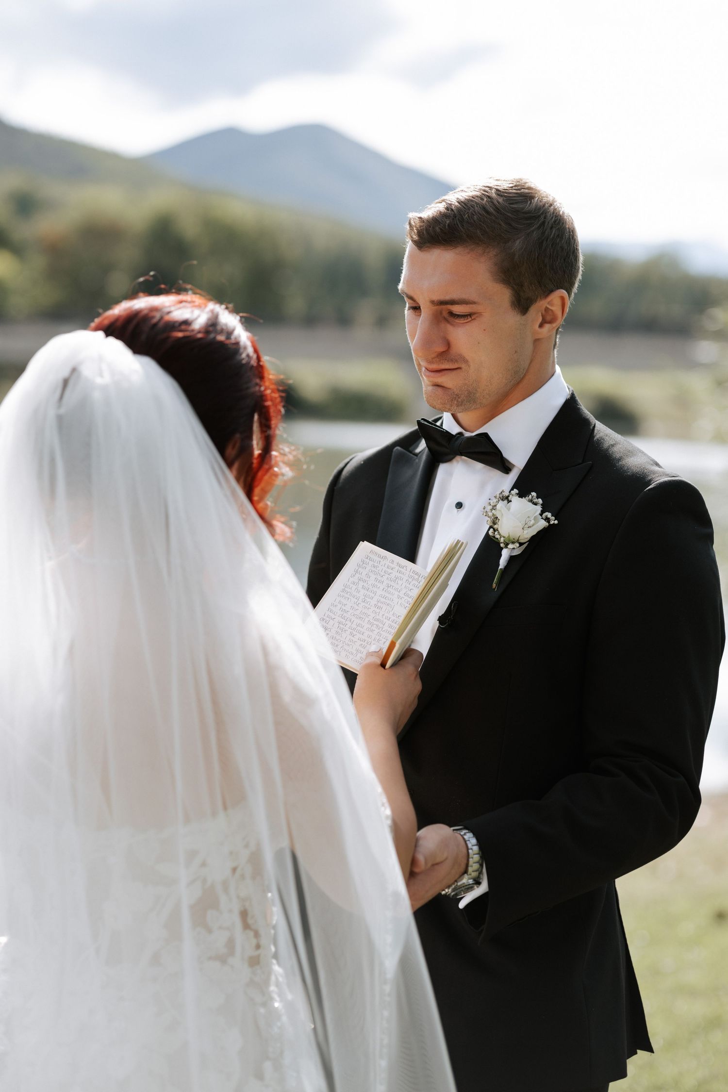 An intimate wedding ceremony moment with mountain scenery and a serene lake backdrop.
