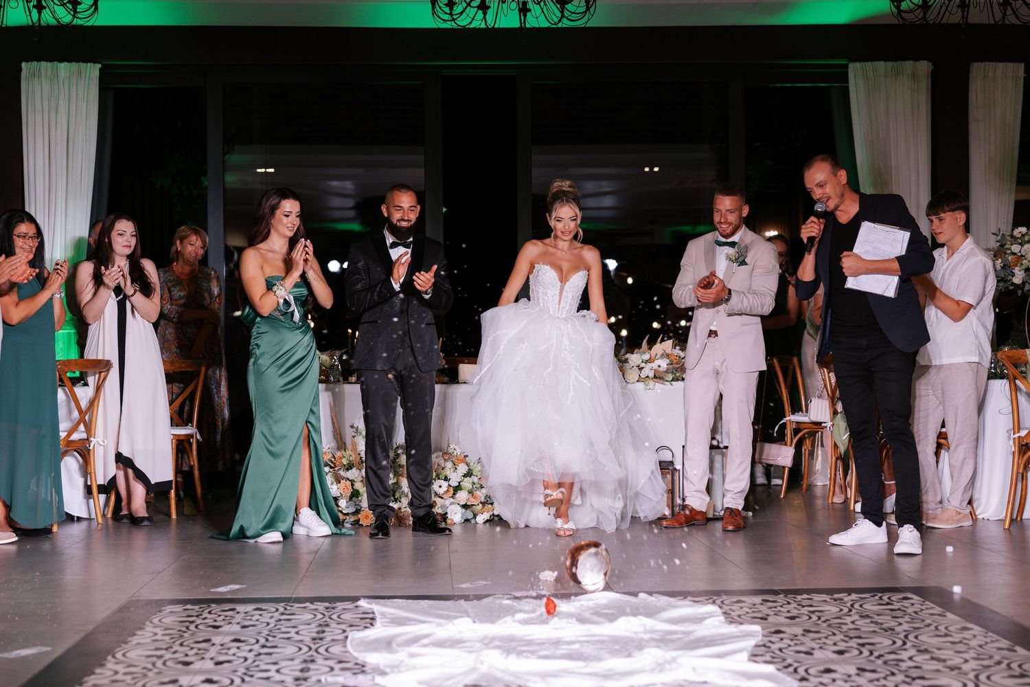 Wedding guests dance together in a line formation on a dance floor during a reception celebration.