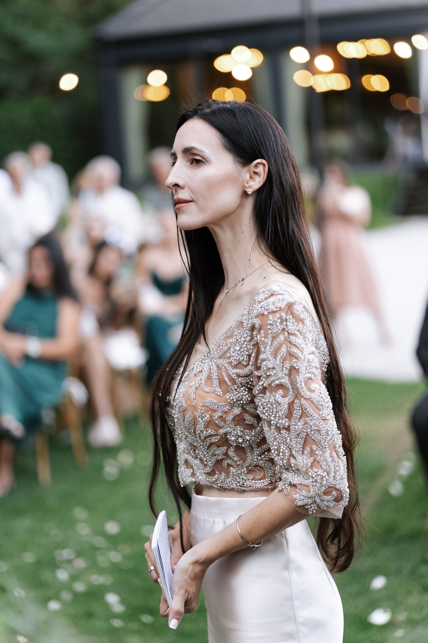 A person in a white lace wedding dress poses outdoors during a summer celebration.