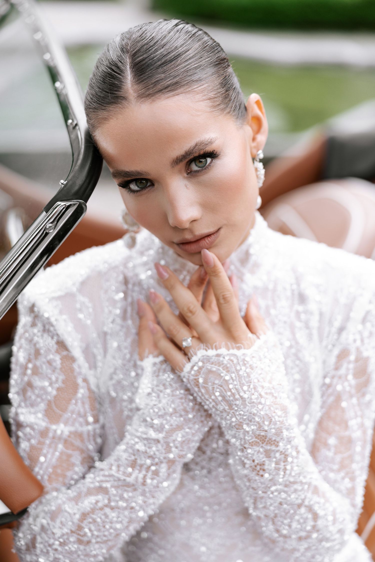 A person in a white lace dress with long sleeves poses in a romantic bridal portrait series.