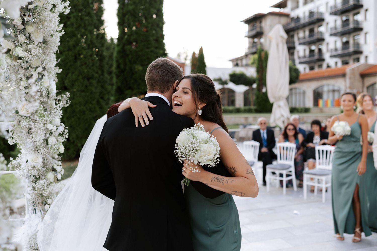 Joyful embrace captured during outdoor wedding with mountain resort backdrop.