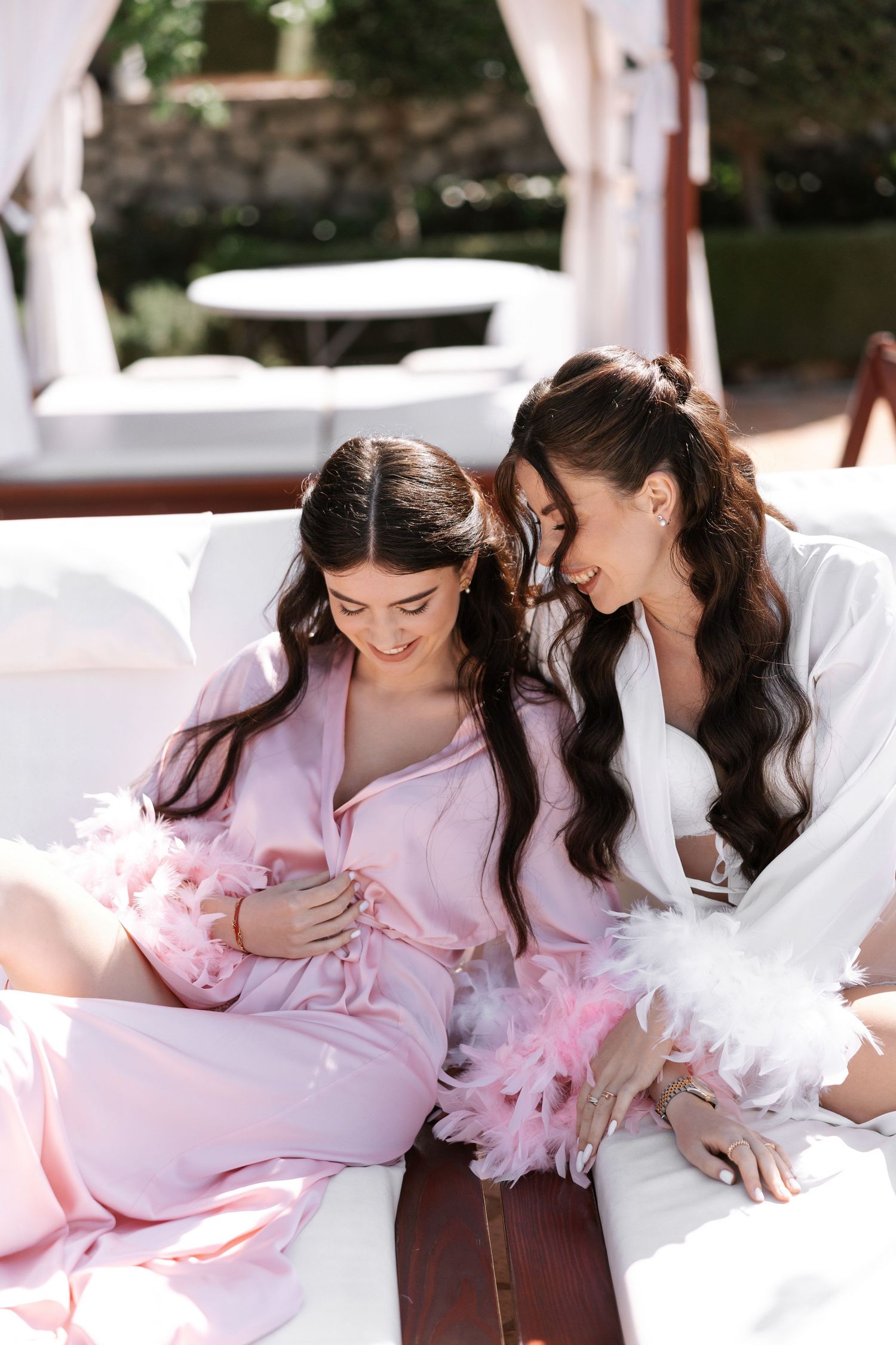 Pink robed figures relaxing on plush white loungers at a luxury resort spa setting.
