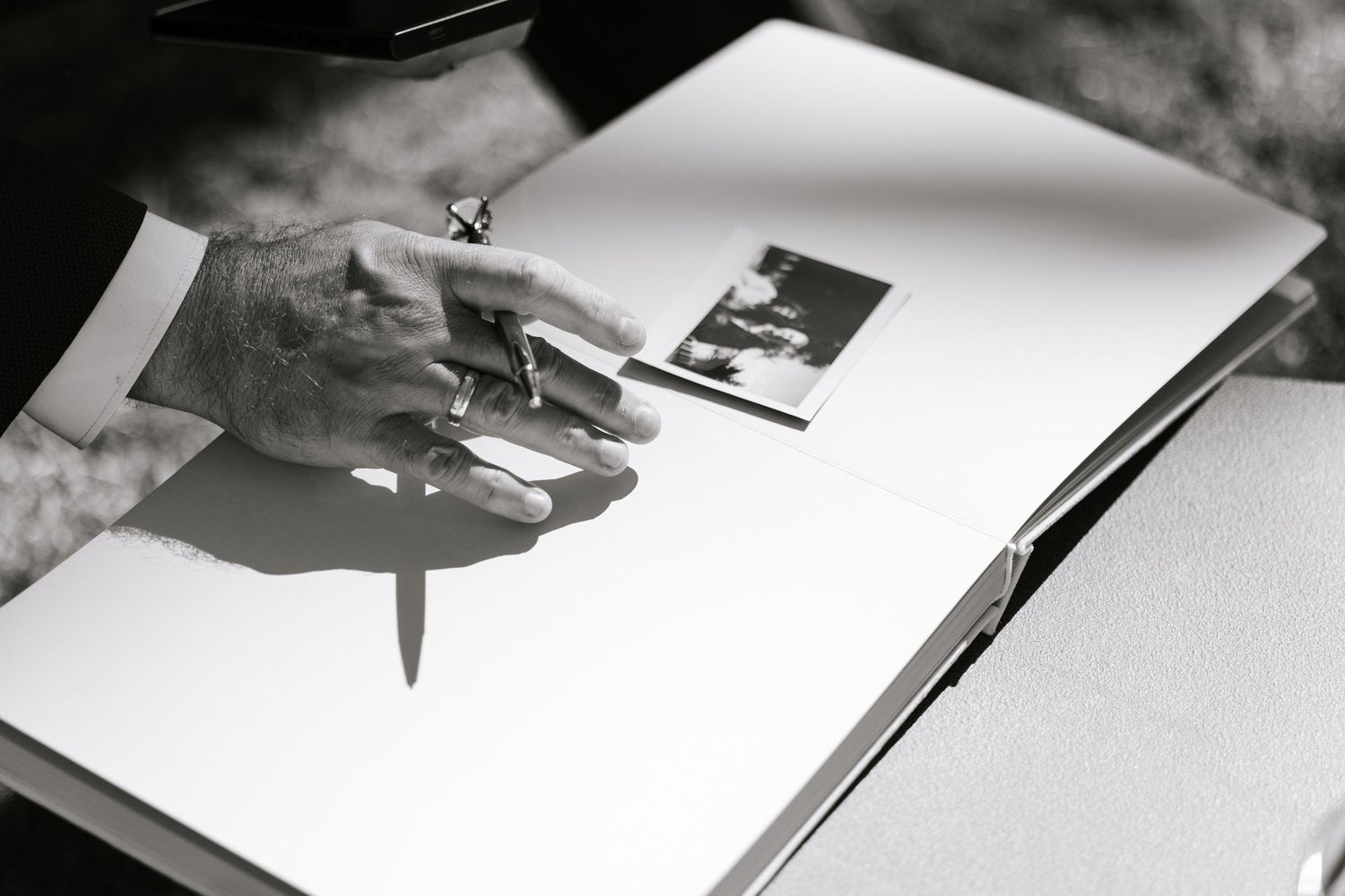 Black and white image showing hands writing or signing documents.
