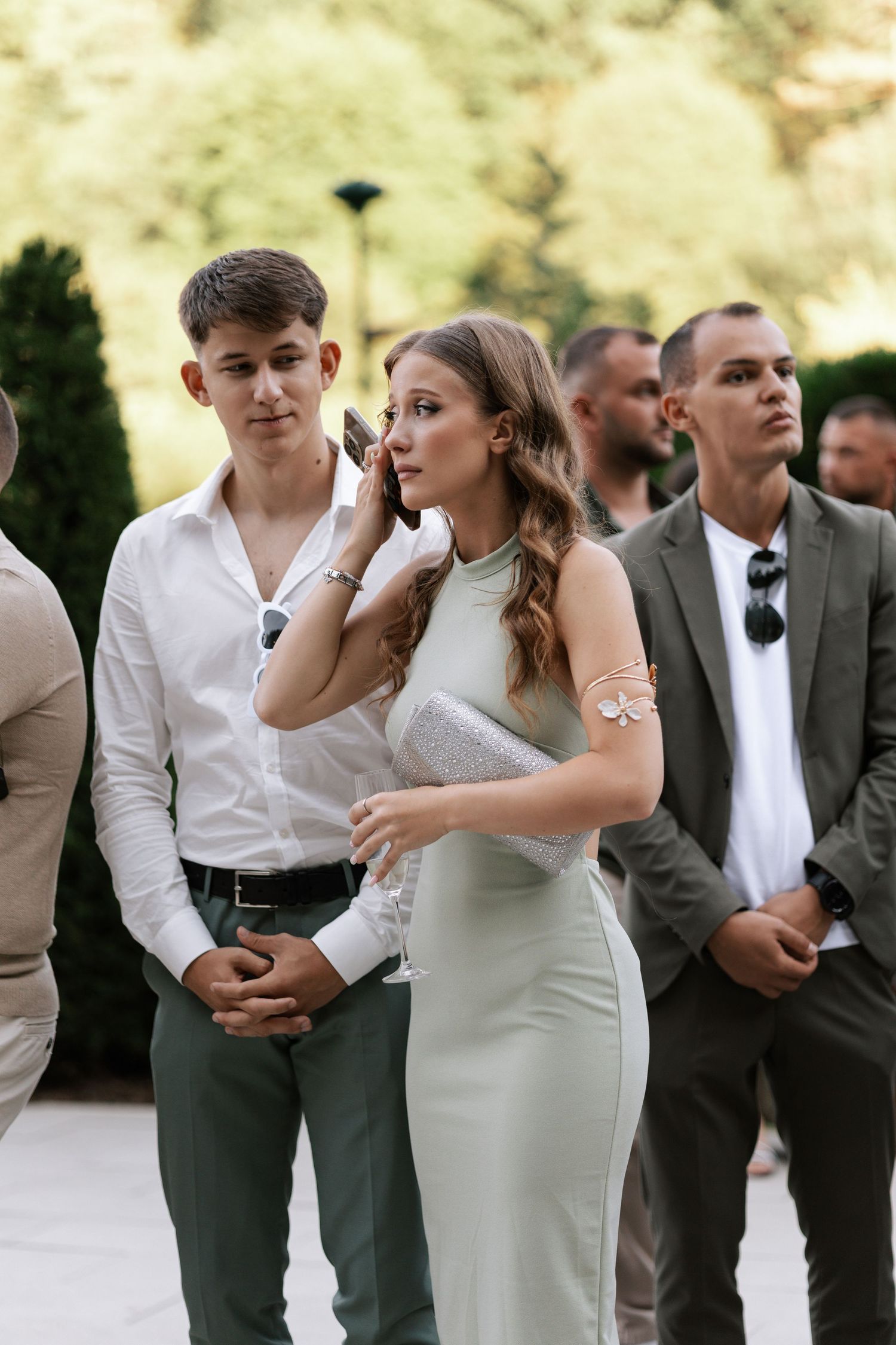 Wedding party members in white shirts and gray suits gather outdoors for candid group photos.