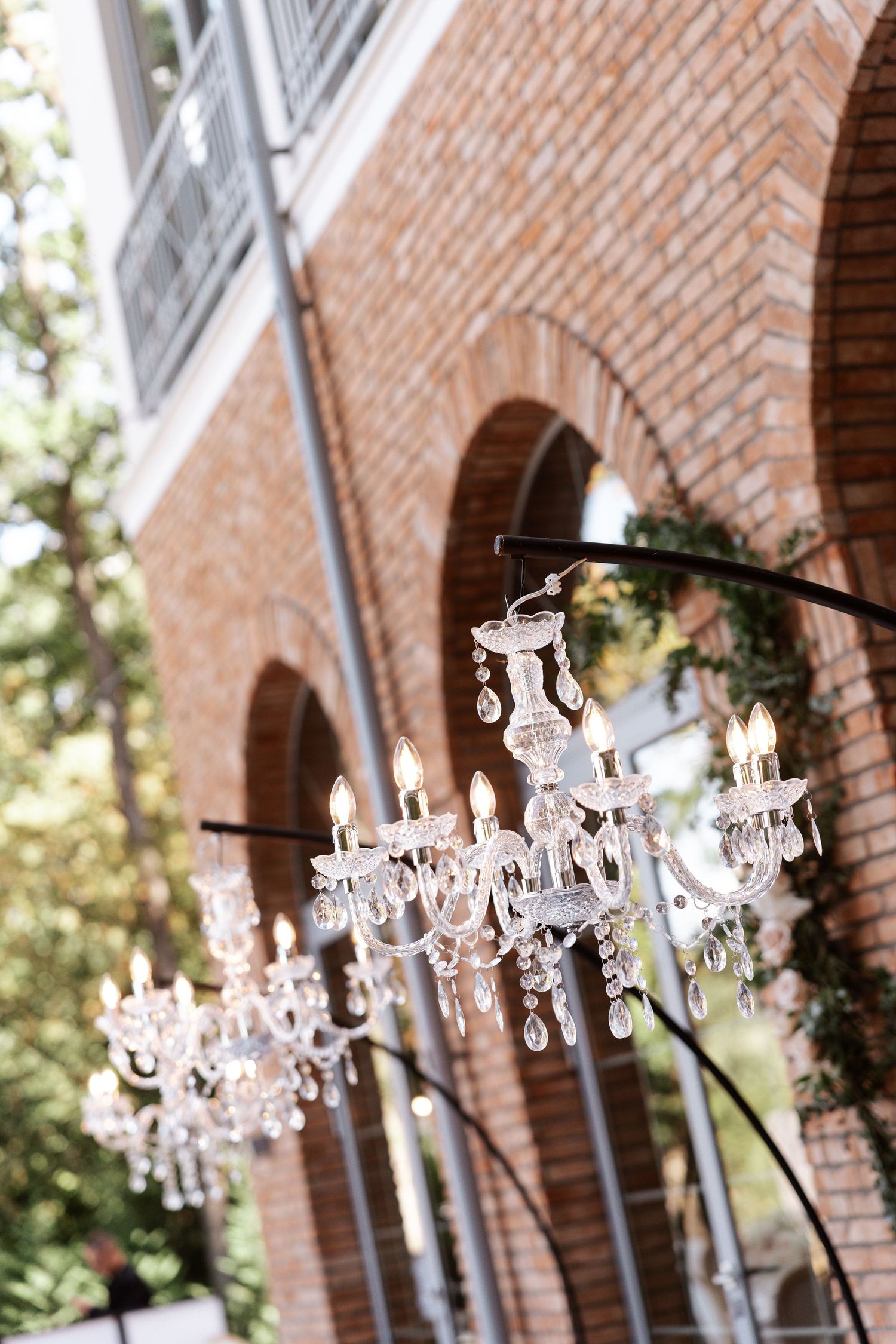 Crystal chandeliers hanging along a brick archway for an elegant outdoor wedding.