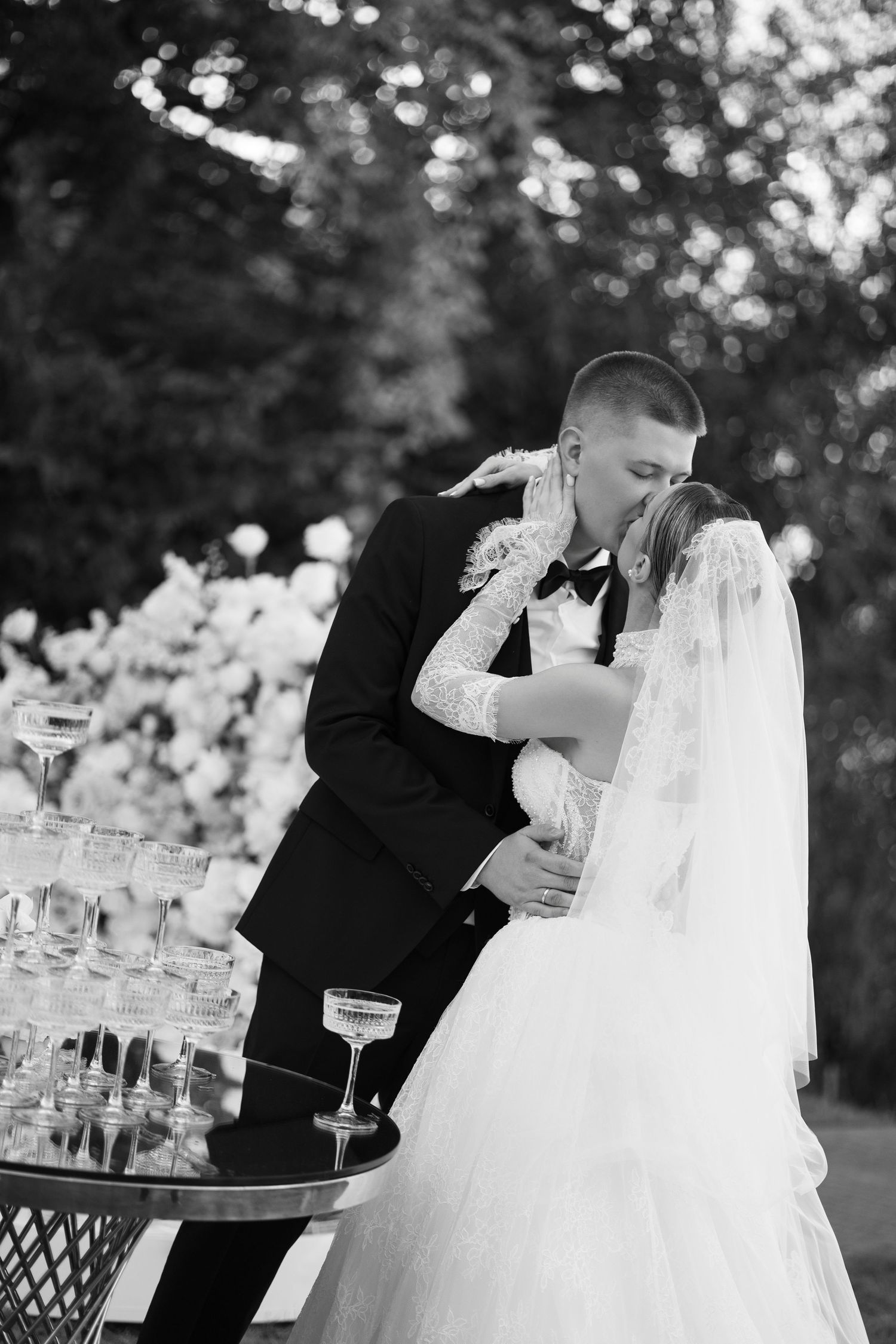 Black and white photo of couple sharing champagne during an elegant outdoor reception.