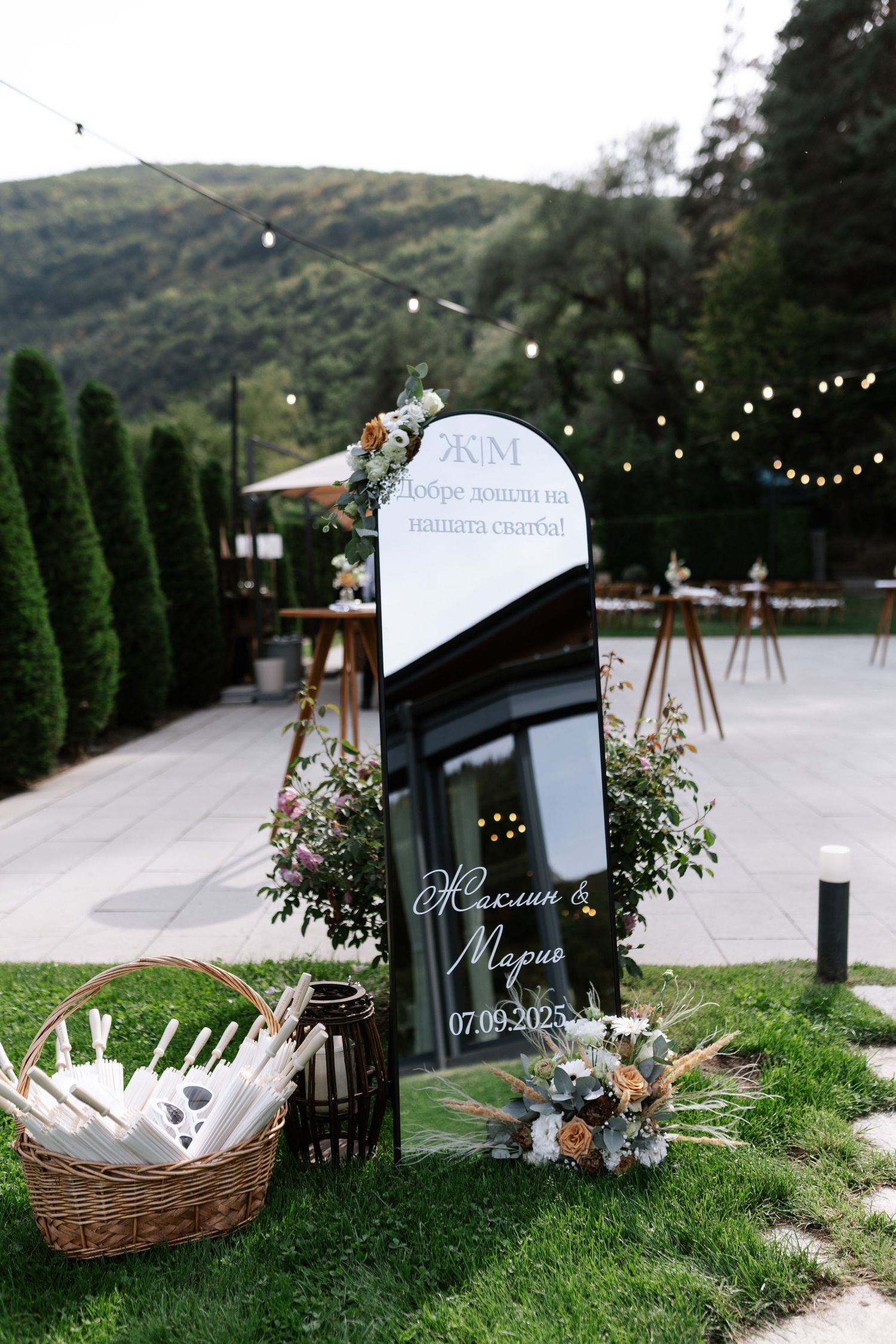 Wedding decorations and signage arranged on grass with string lights and baskets creating a romantic outdoor atmosphere.