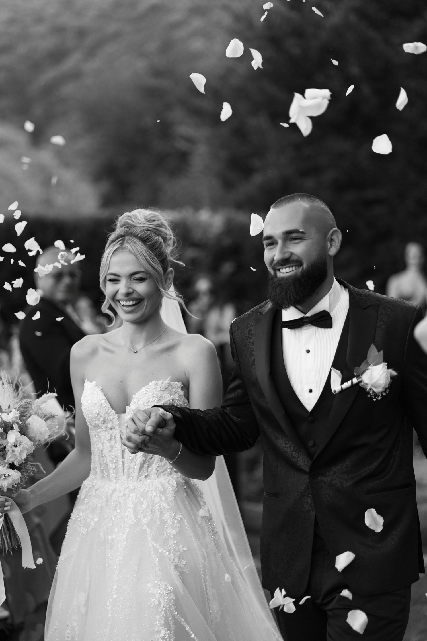A joyful black and white wedding photo sequence showing a couple celebrating with rose petals being tossed in the air.
