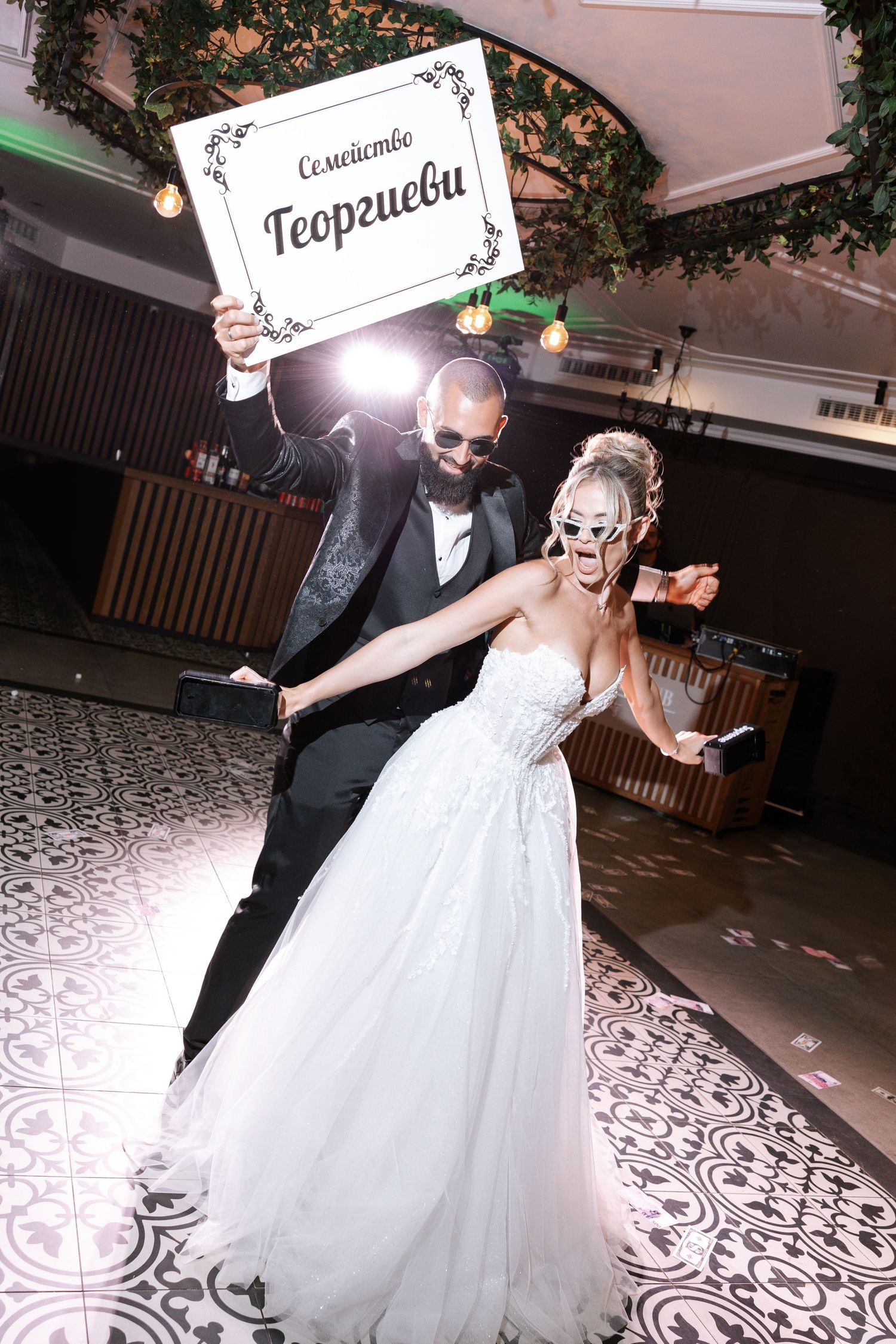 A couple in wedding attire performs a romantic dance together on a patterned dance floor at their reception.