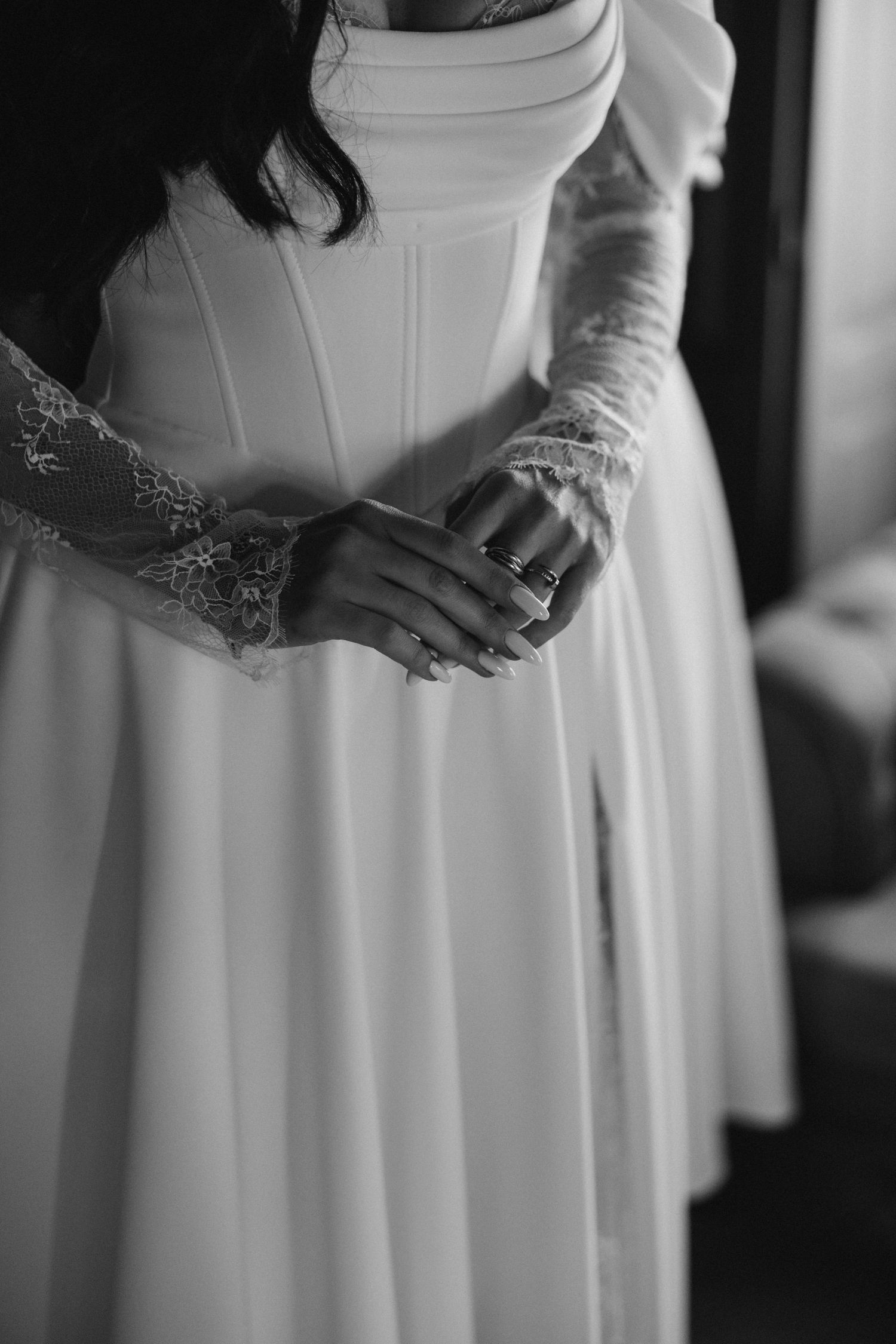 Black and white detail shots of a bride's white wedding dress with delicate lace details and flowing fabric.