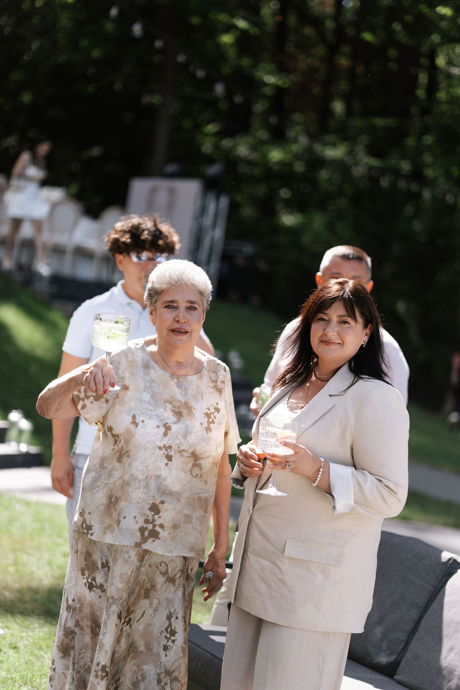 Wedding guests in coordinated beige outfits enjoying an outdoor celebration.
