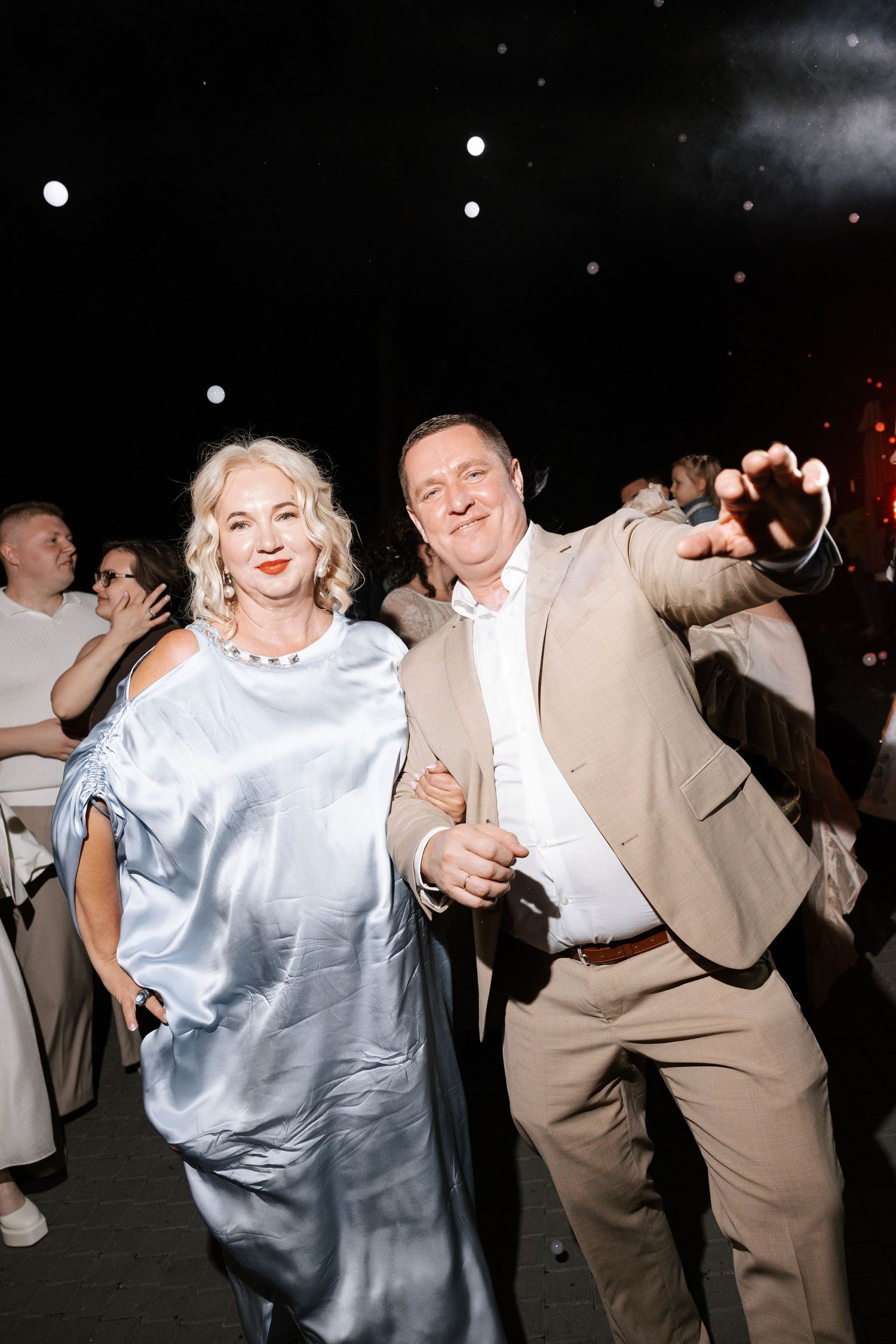 Couples dance together at a wedding reception with festive lighting.