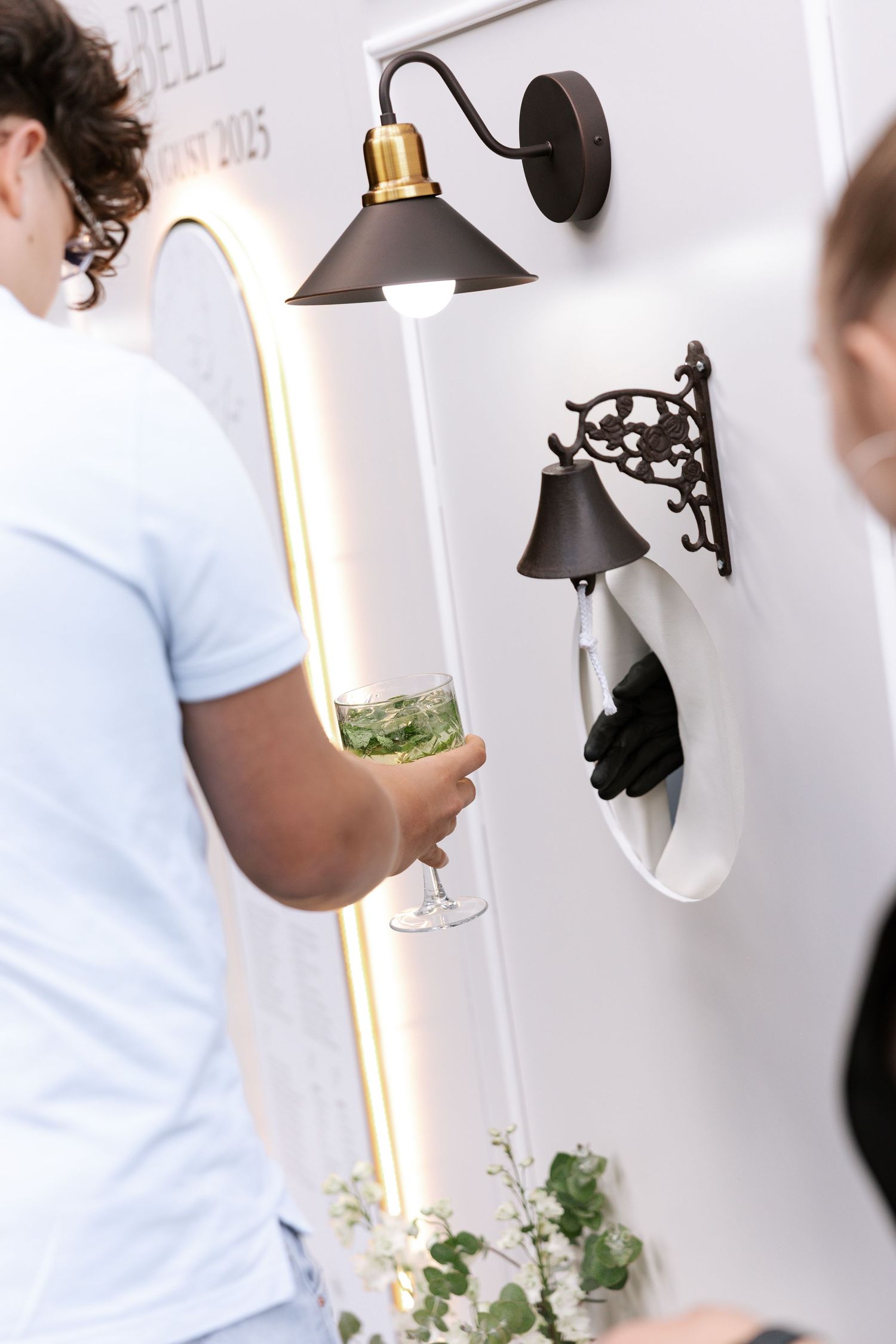 Close-up of someone adjusting black wall sconces in a bright white interior space.