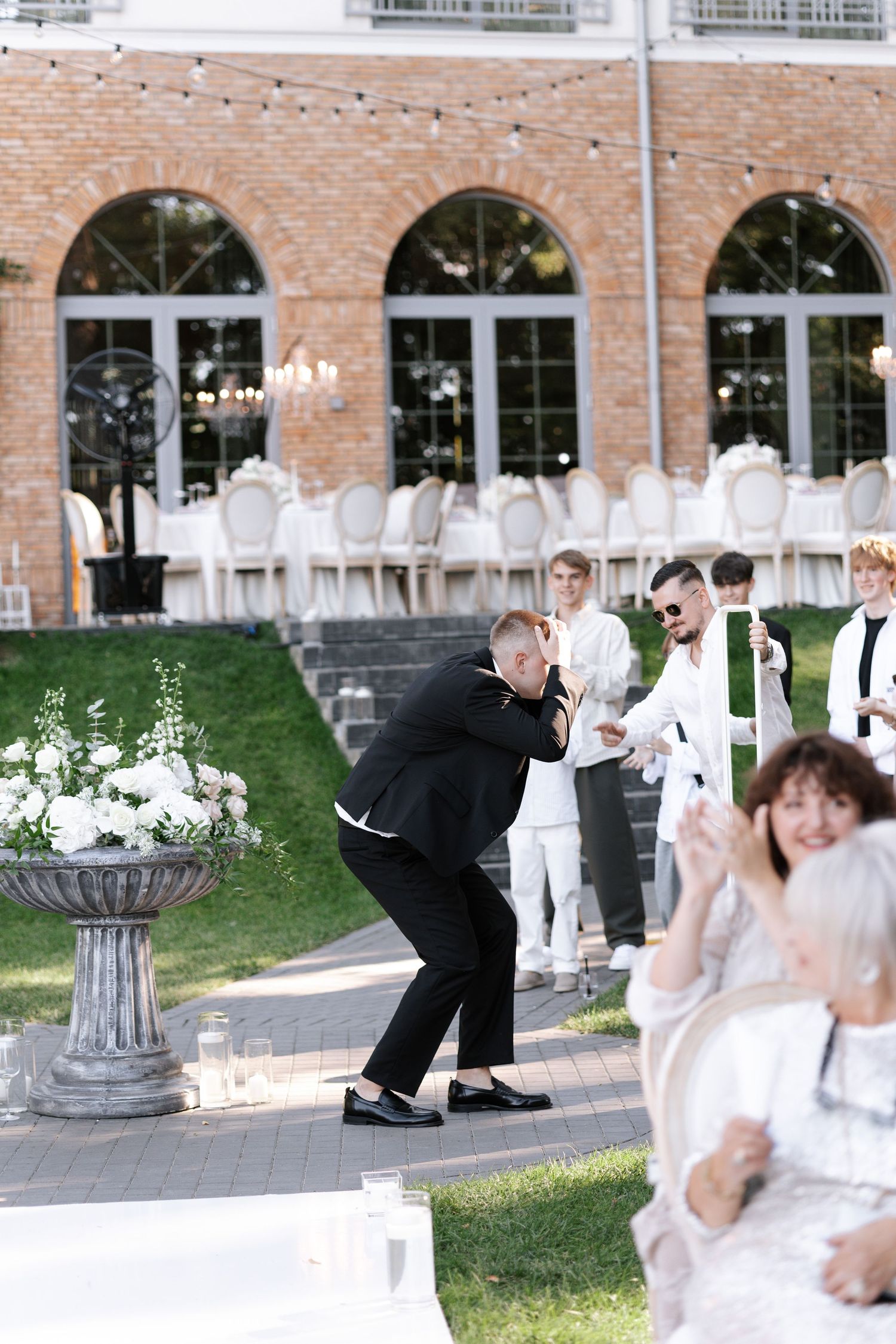 Wedding celebration outside a brick building with guests dancing on the patio.