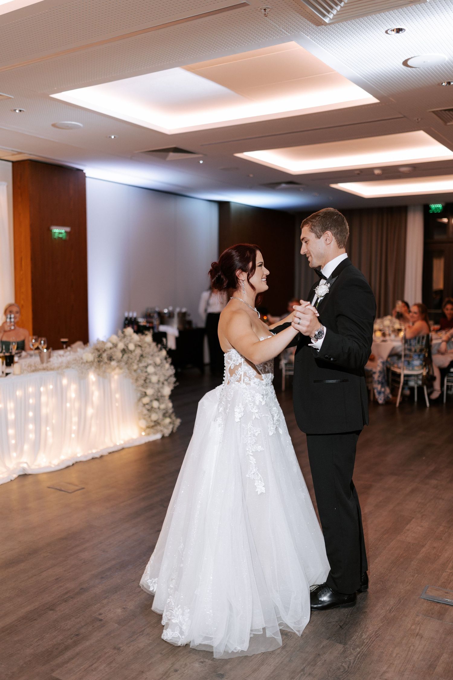 Newlyweds share their first dance in an elegant reception hall.