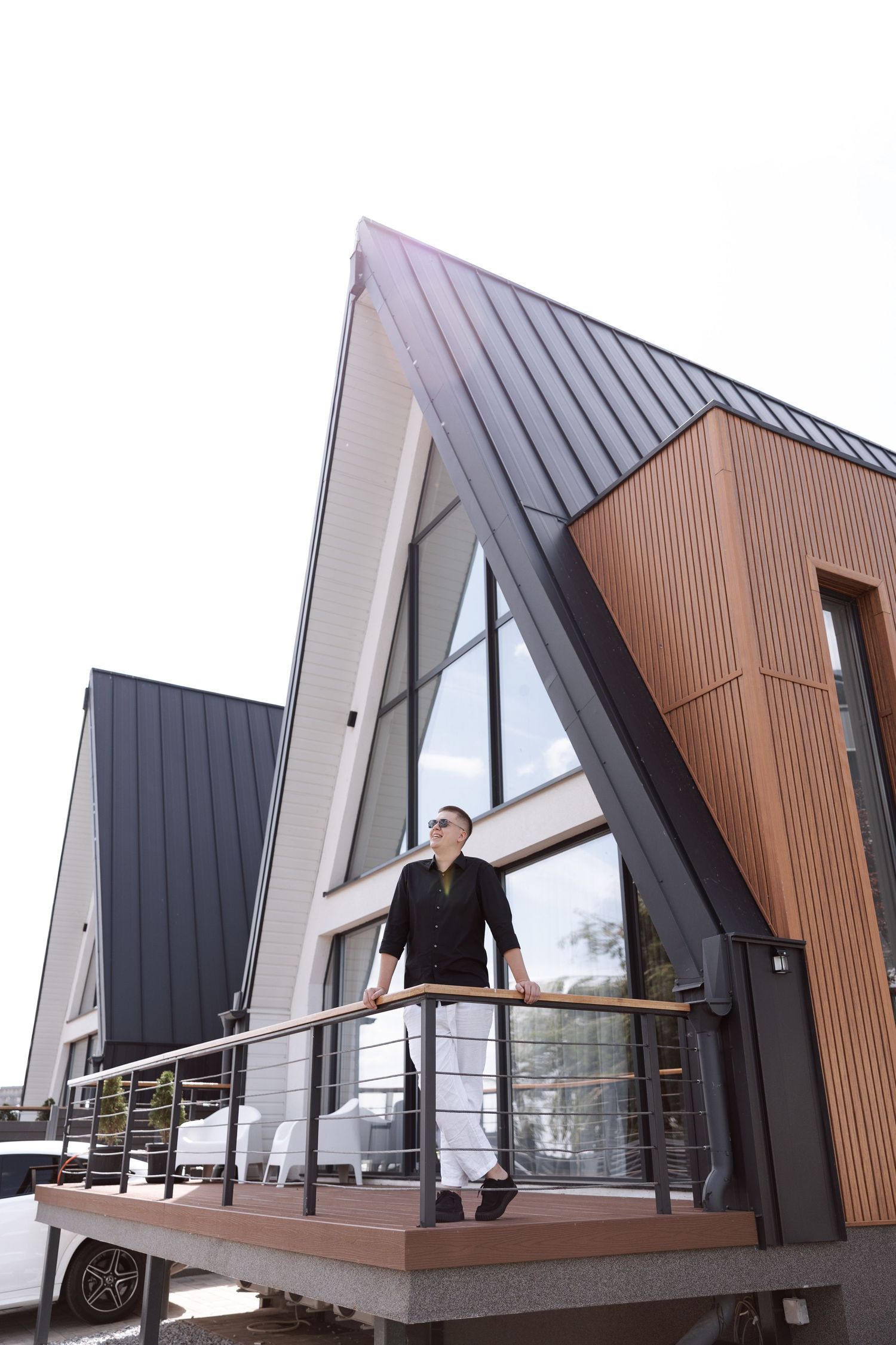 Modern A-frame house exterior with wood paneling and metal roof details.