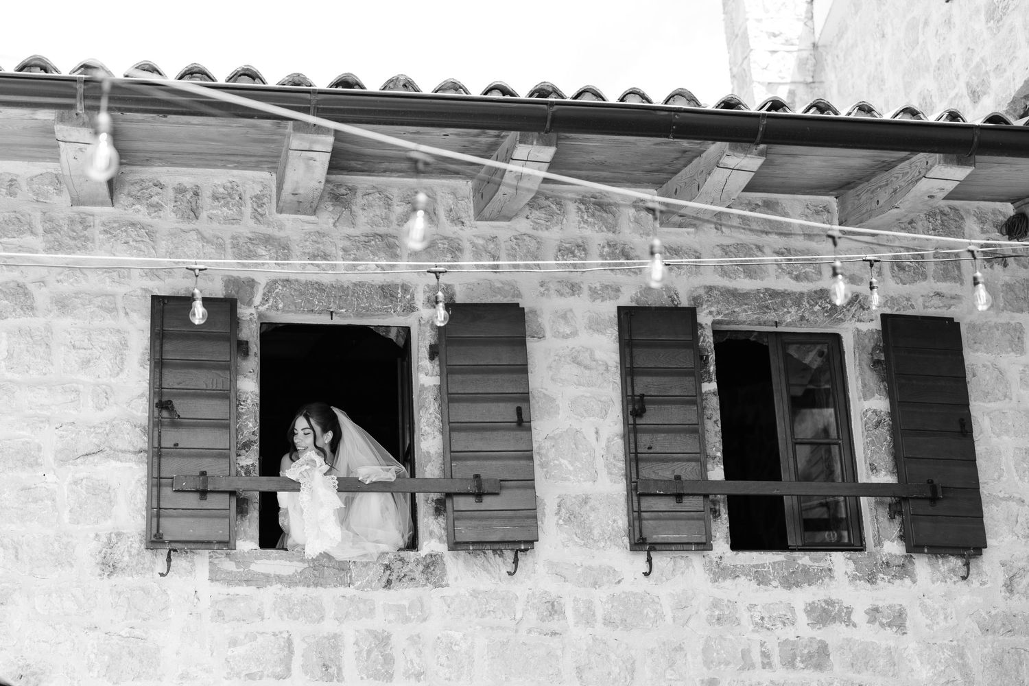 A row of weathered wooden window shutters on a stone building with rustic architectural details.