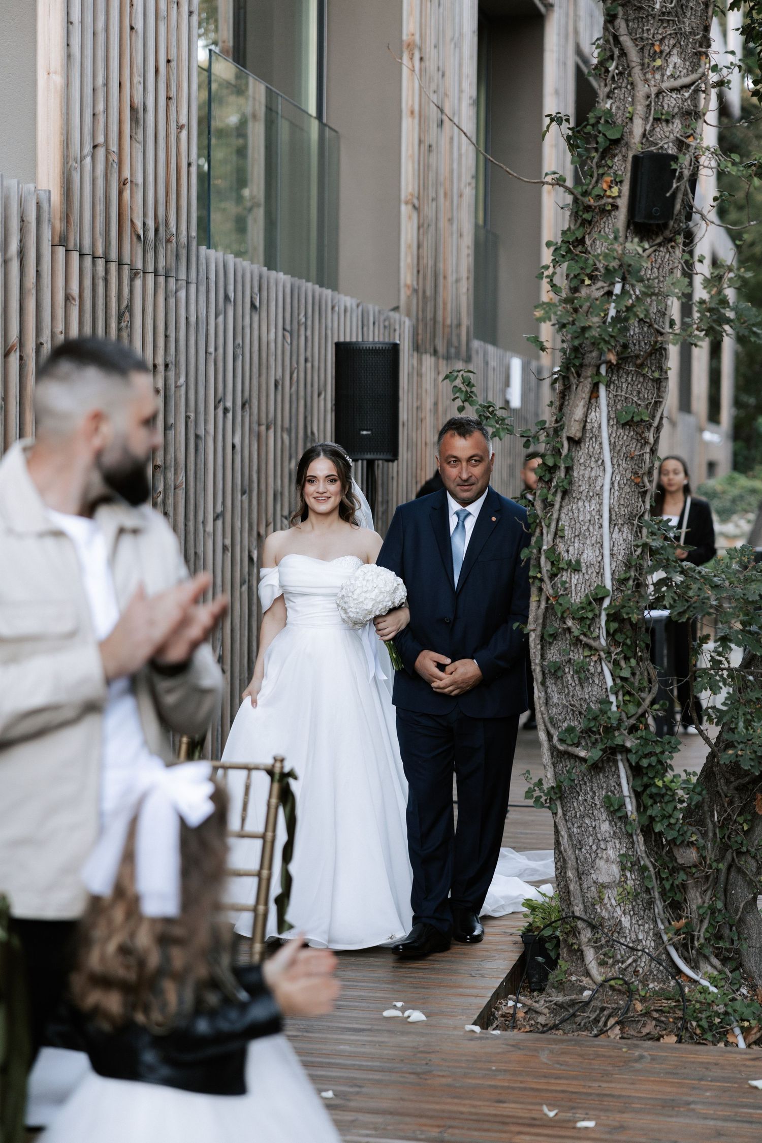 An intimate outdoor wedding ceremony procession with modern architectural details.