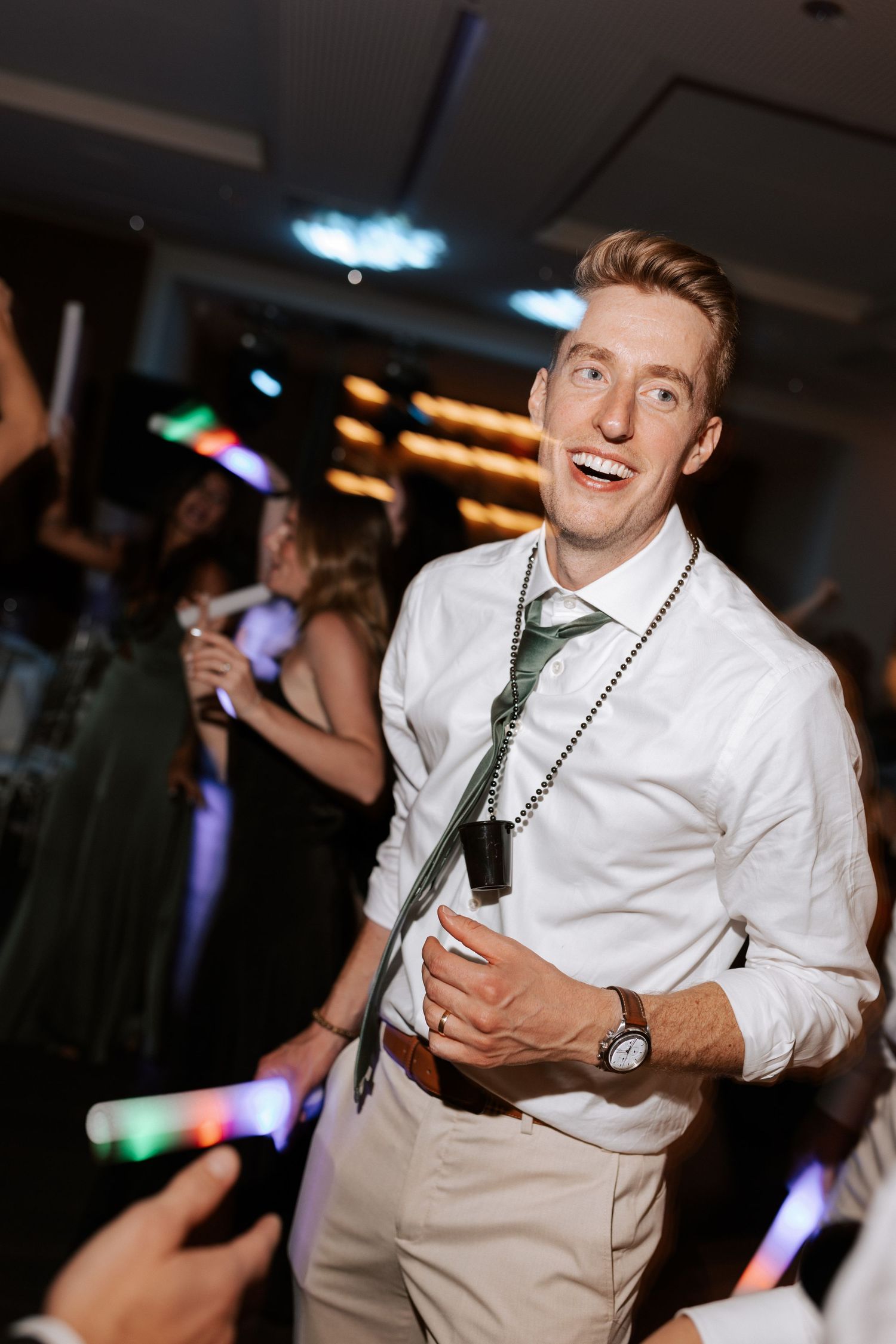 Guest in crisp white shirt and khaki pants dances while holding a light-up party favor.