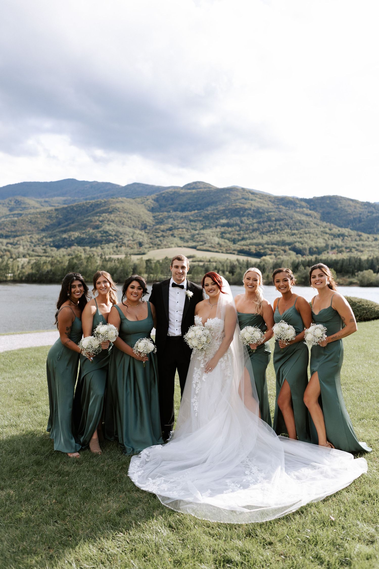 Bridal party in sage green dresses poses against mountain lake backdrop.Wedding photographer Bulgaria