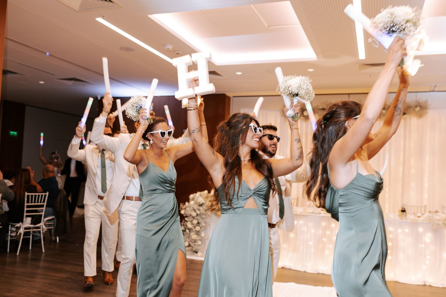 Wedding celebration with light-up foam sticks and party atmosphere in reception venue.