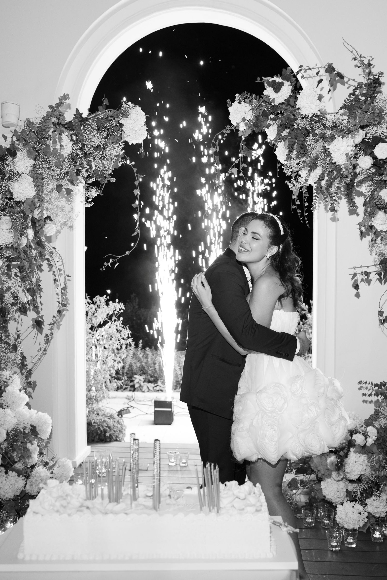 A couple shares their first dance as newlyweds under twinkling lights and floral decorations at an elegant reception.