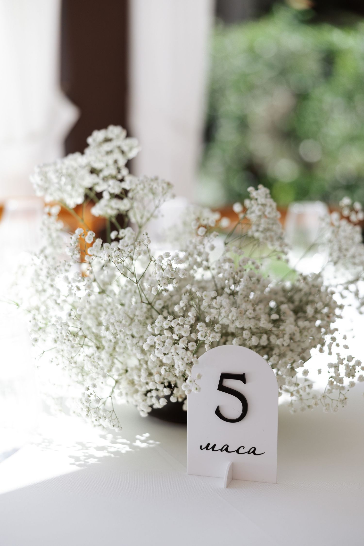Small table number cards with baby's breath flowers create an elegant wedding table setting display.