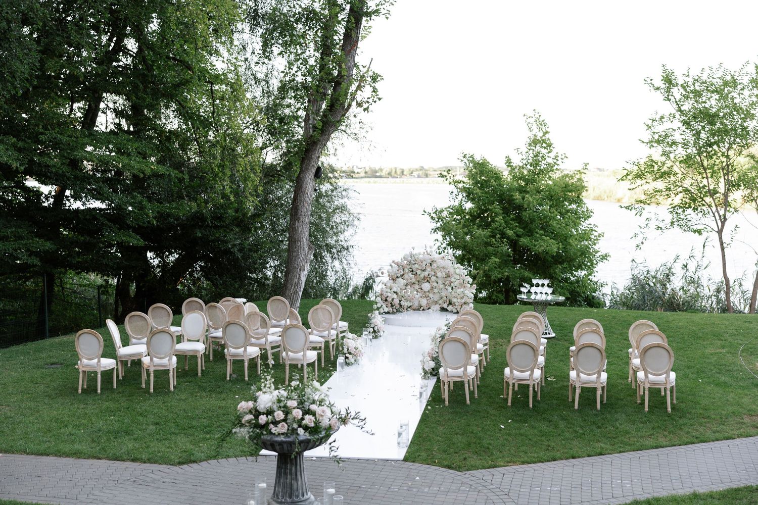 White chairs arranged in rows on a grassy lawn overlooking a waterfront setting for an outdoor wedding.