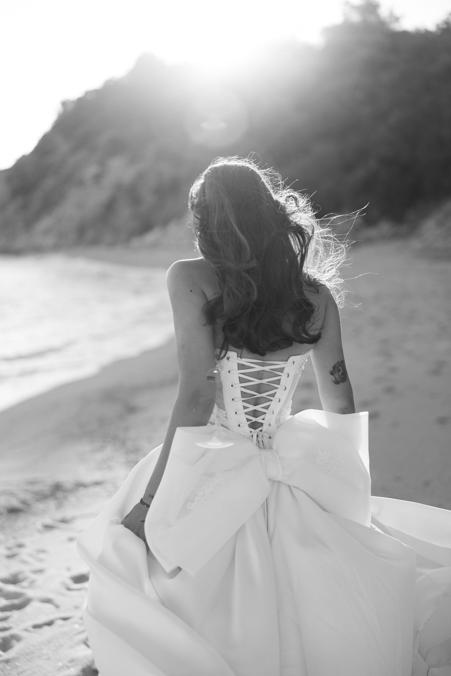 Black and white photos show a bride in a flowing white dress with corset back detail running on a beach.