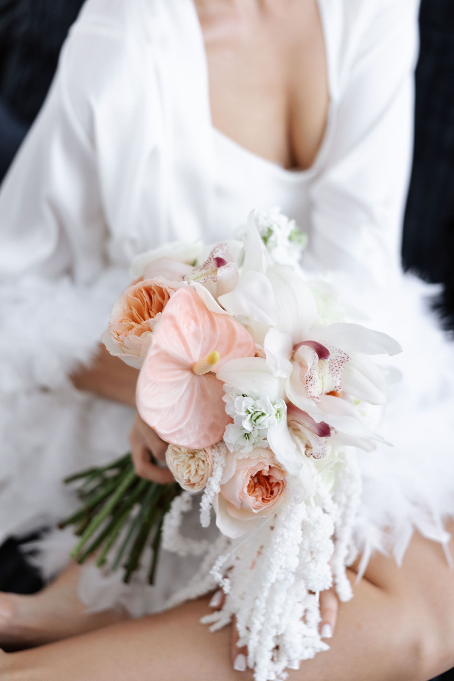 Close-up of an elegant wedding bouquet with blush pink and white flowers against a white background.
