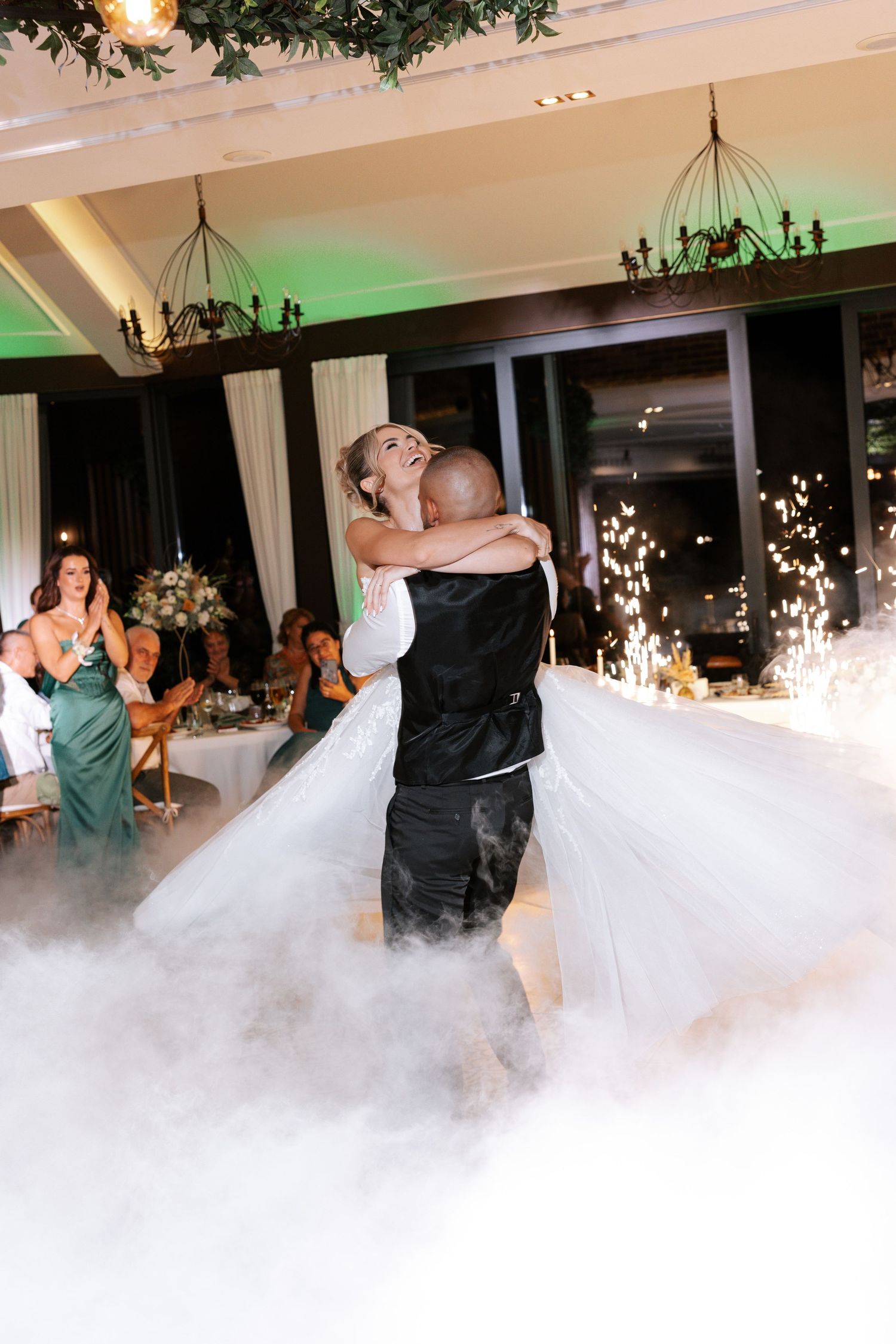 Newlyweds share their first dance surrounded by romantic fog on the dance floor at an elegant wedding reception.