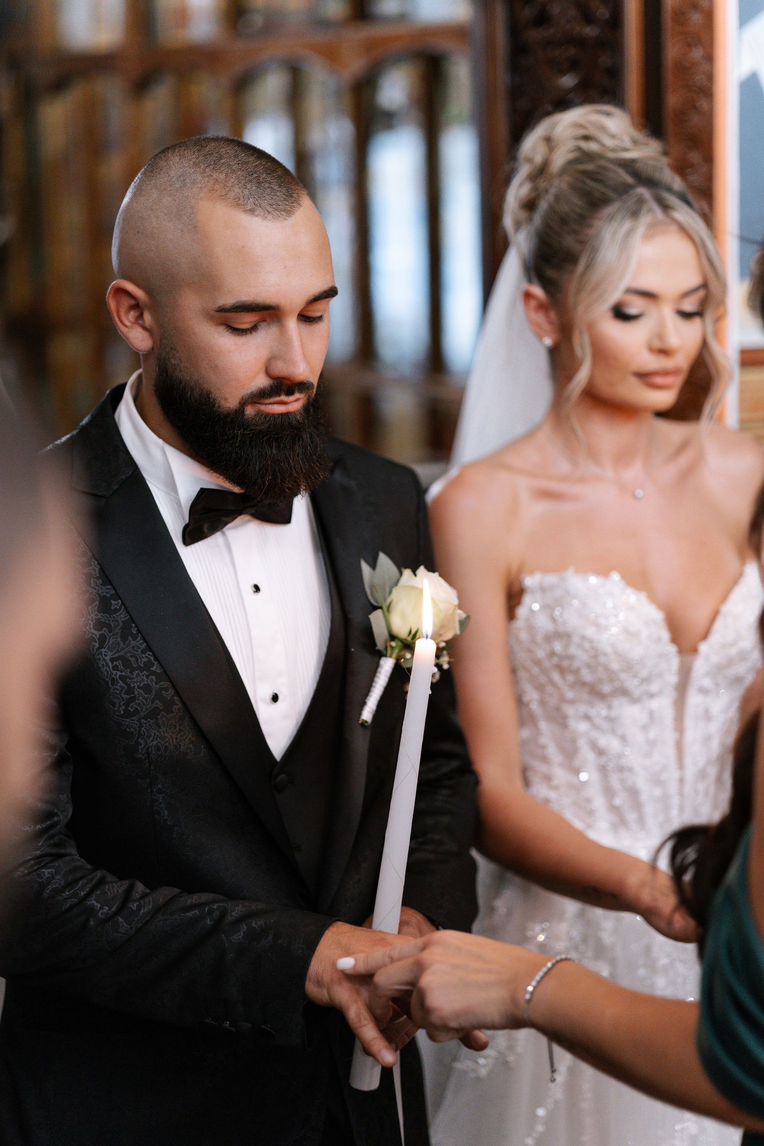 A wedding ceremony moment showing a couple at the altar with the groom holding a candle during their traditional service.