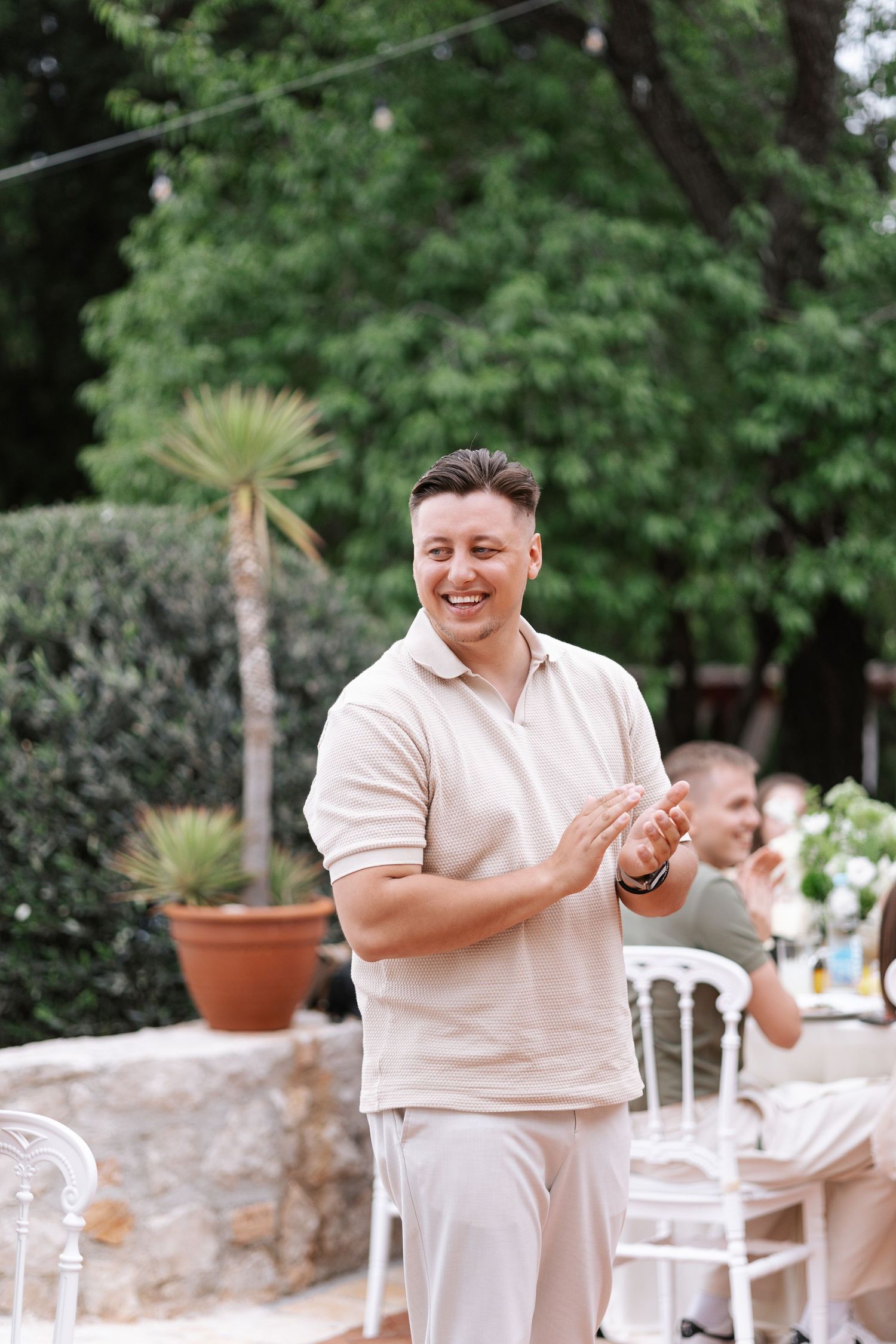 A cheerful outdoor celebration with potted plants and white chairs in a garden setting.