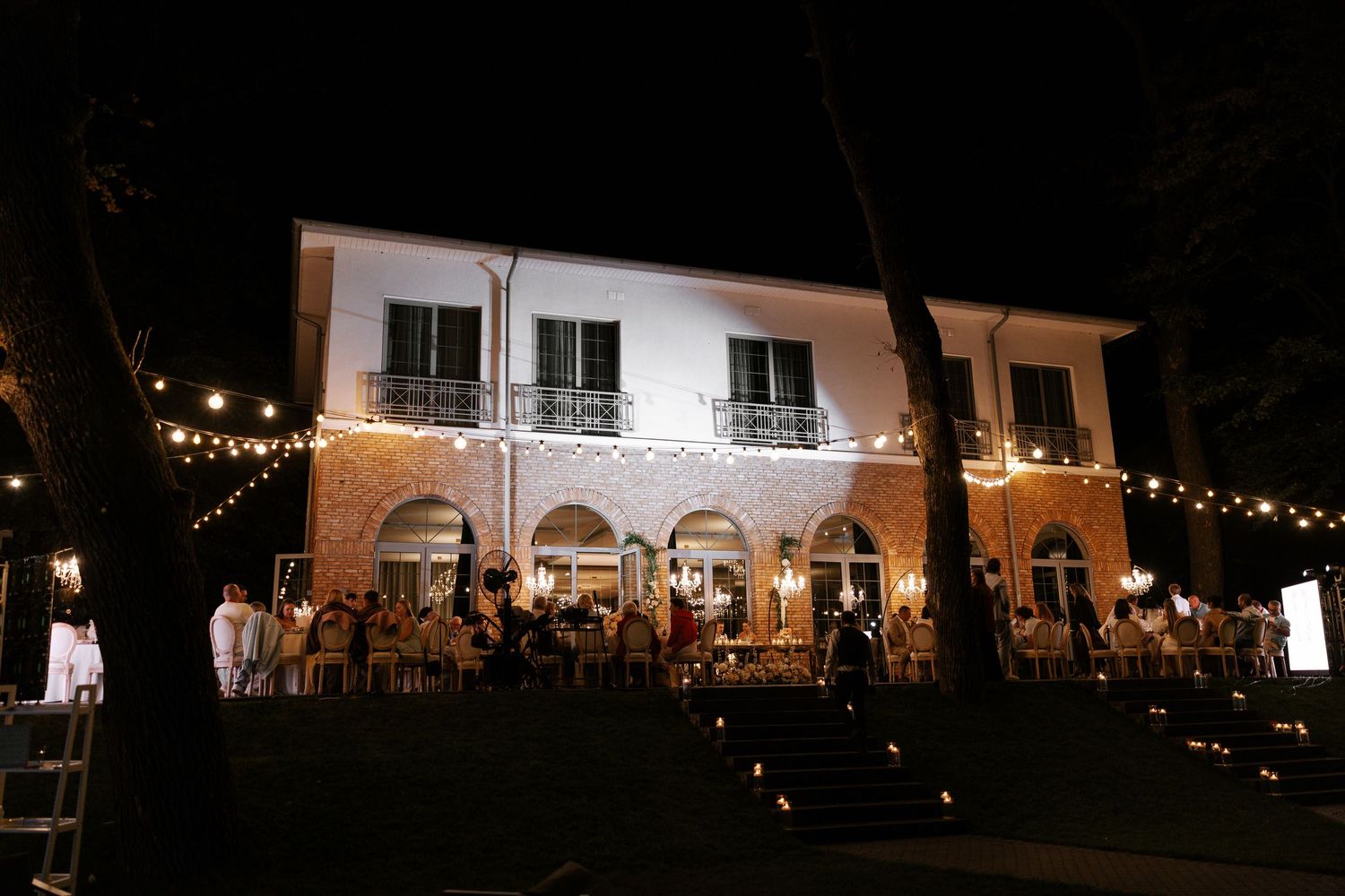 A wedding venue illuminated with string lights at night creates a romantic atmosphere.