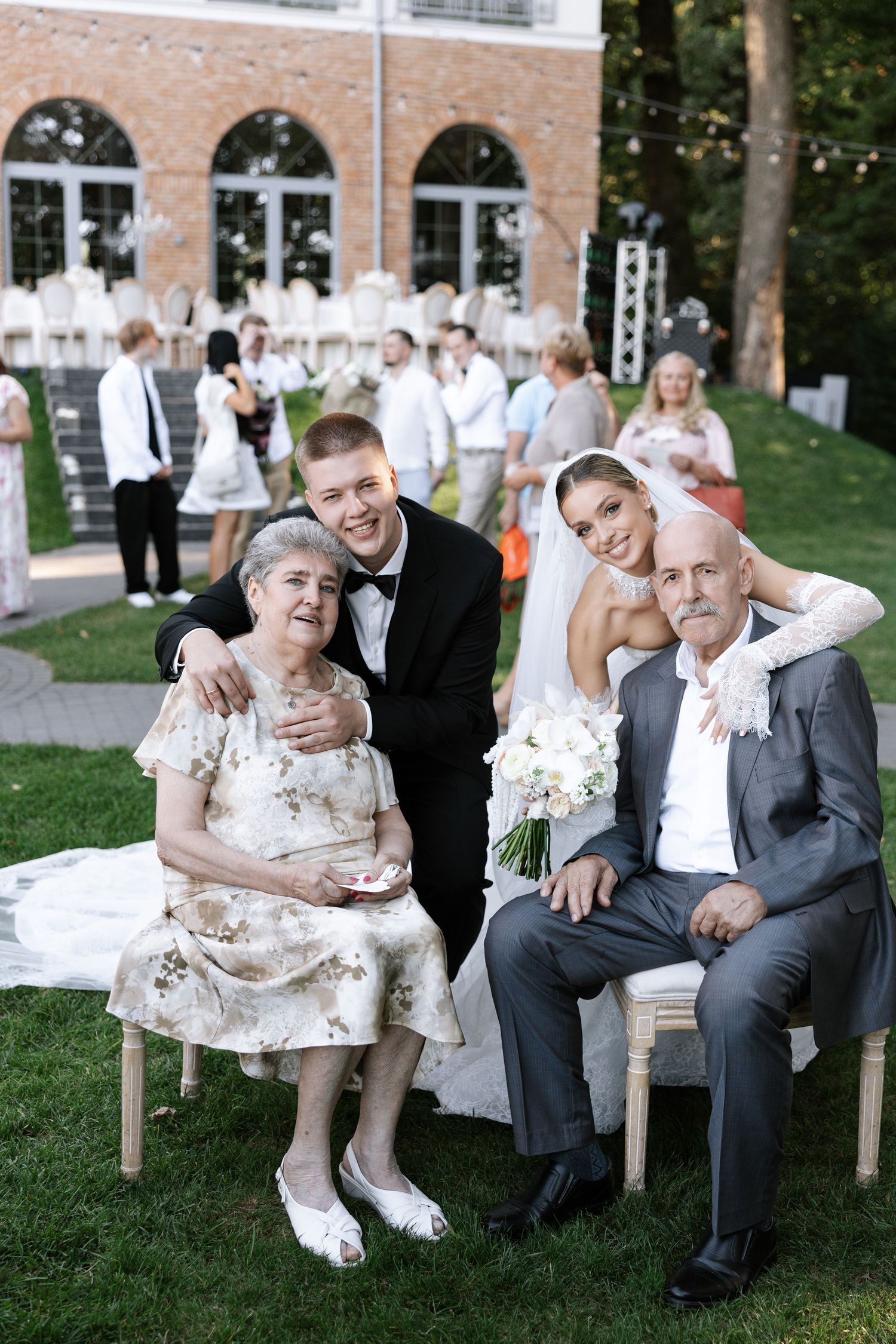 Elderly couple shares tender moments on outdoor benches during a wedding celebration.