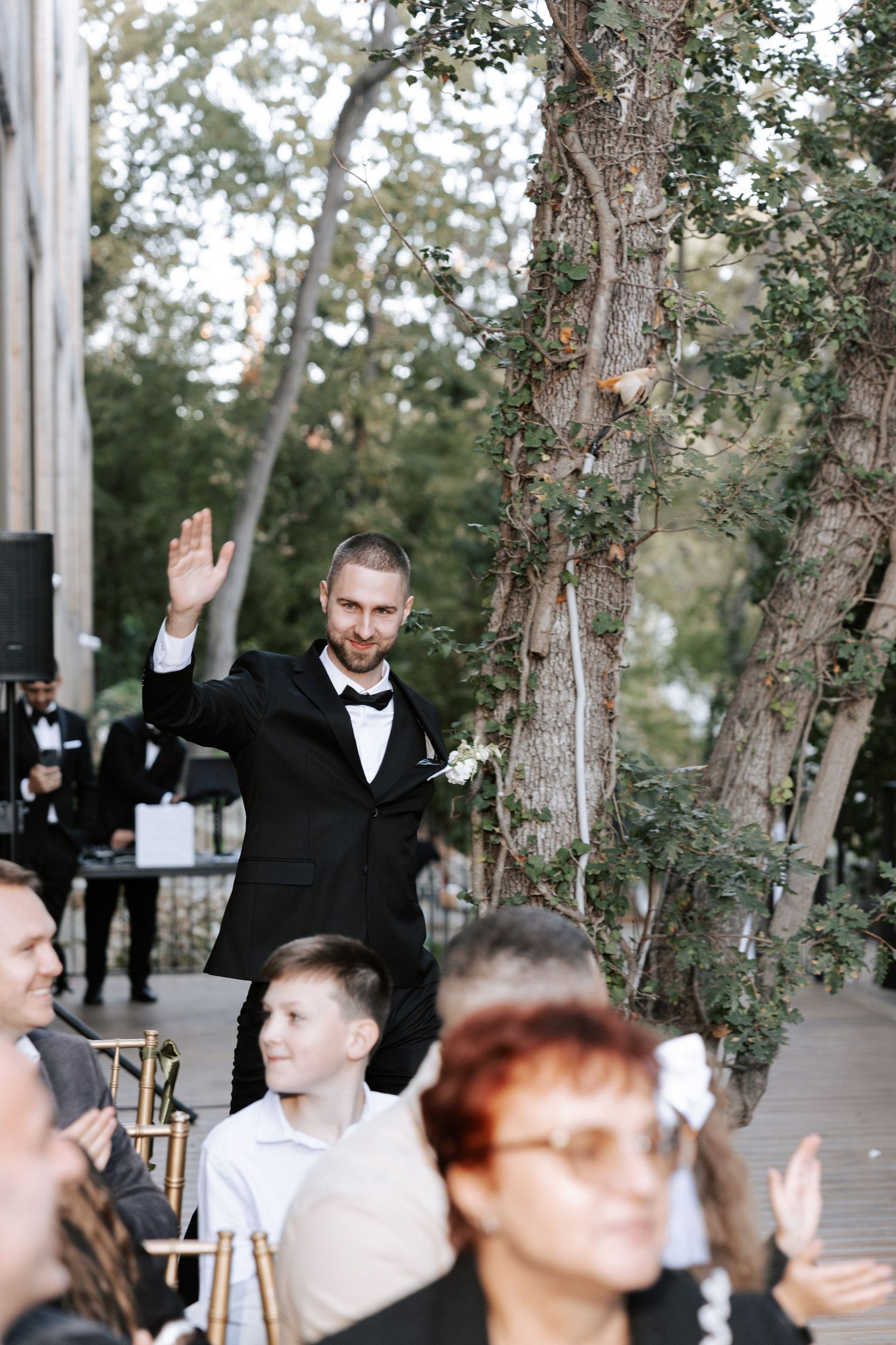 A speaker addresses the wedding guests during an outdoor forest ceremony.