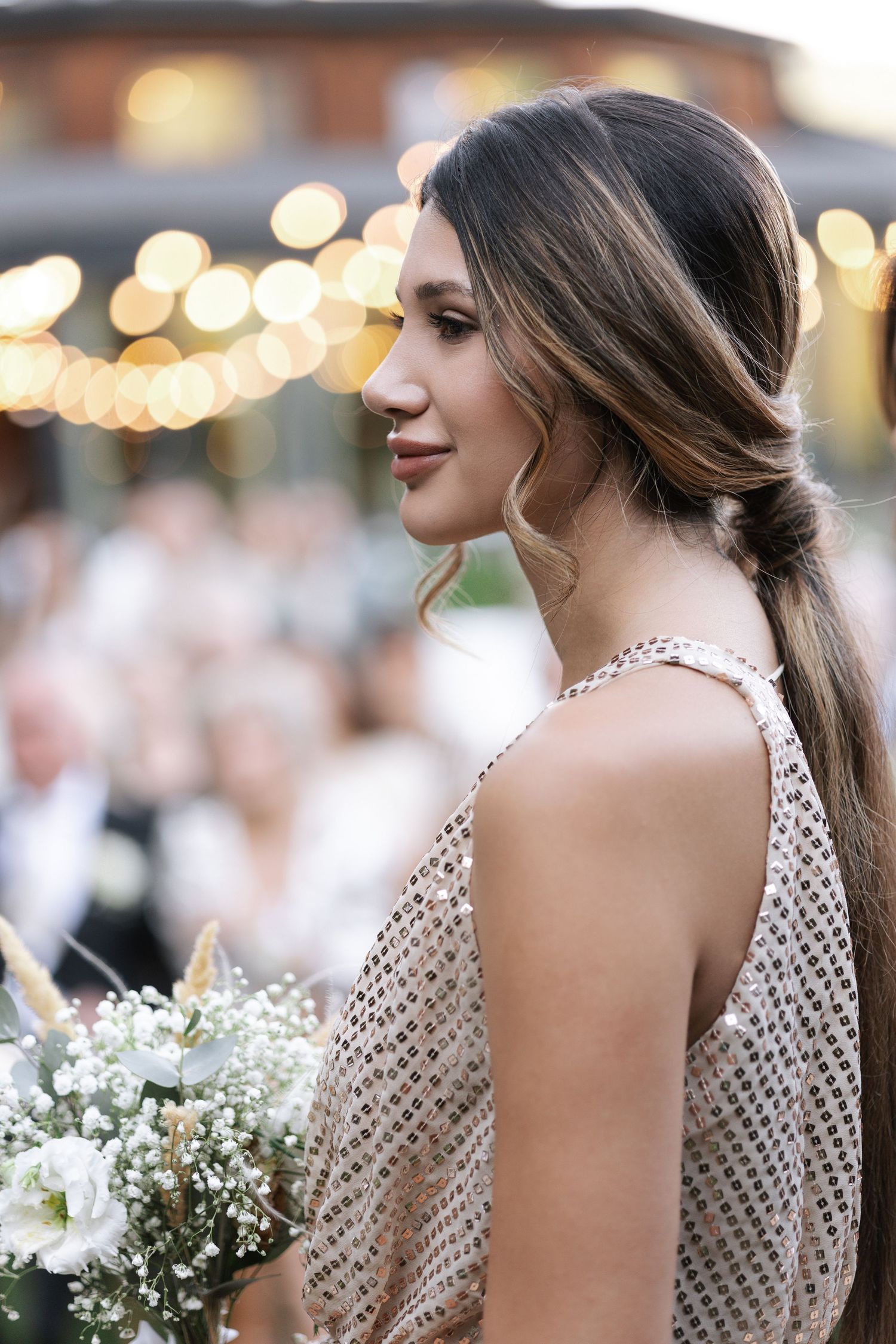 Row of bridesmaids in polka dot dresses holding white floral bouquets at an evening reception.