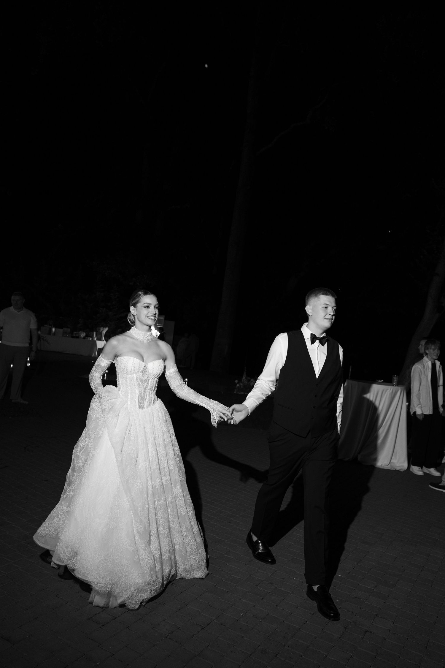 Black and white photo of couple dancing at outdoor wedding reception.