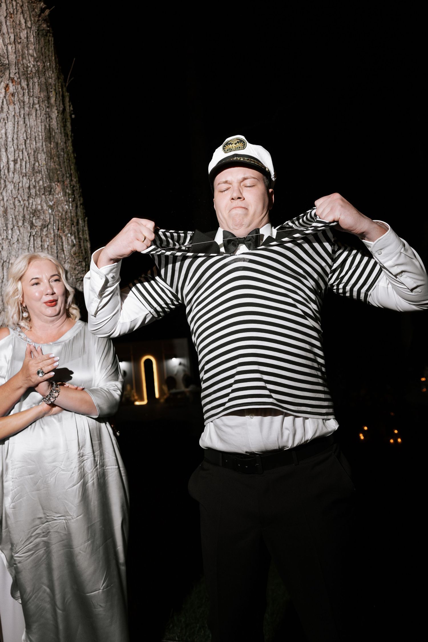 Wedding guests in striped and casual attire celebrating enthusiastically at night.
