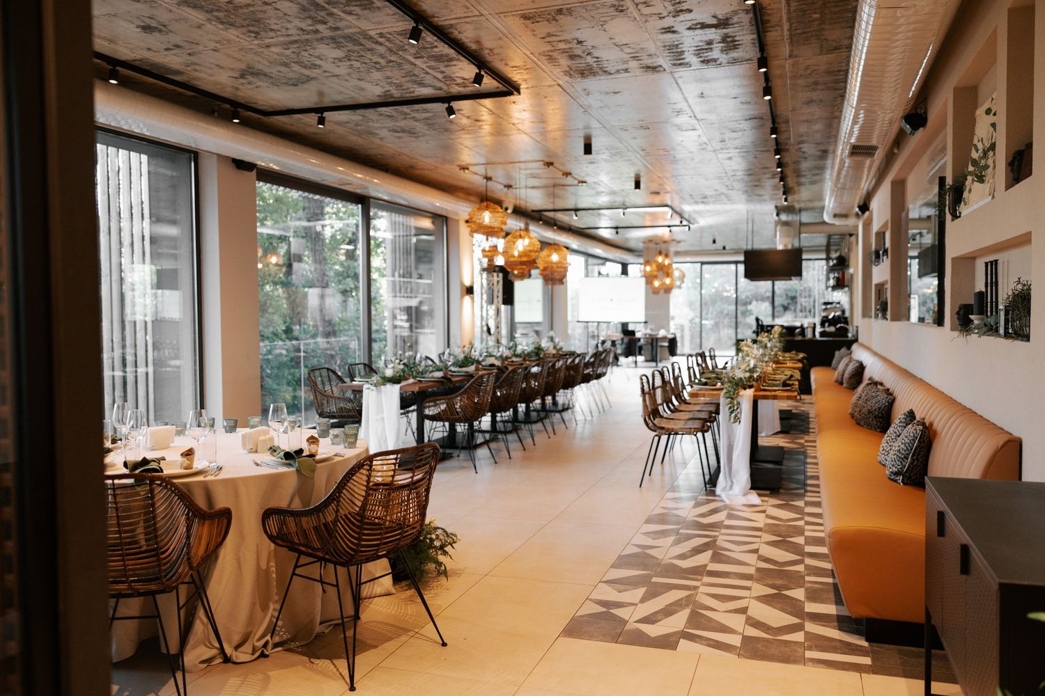 Modern restaurant interior with large windows, wooden chairs and geometric floor pattern.