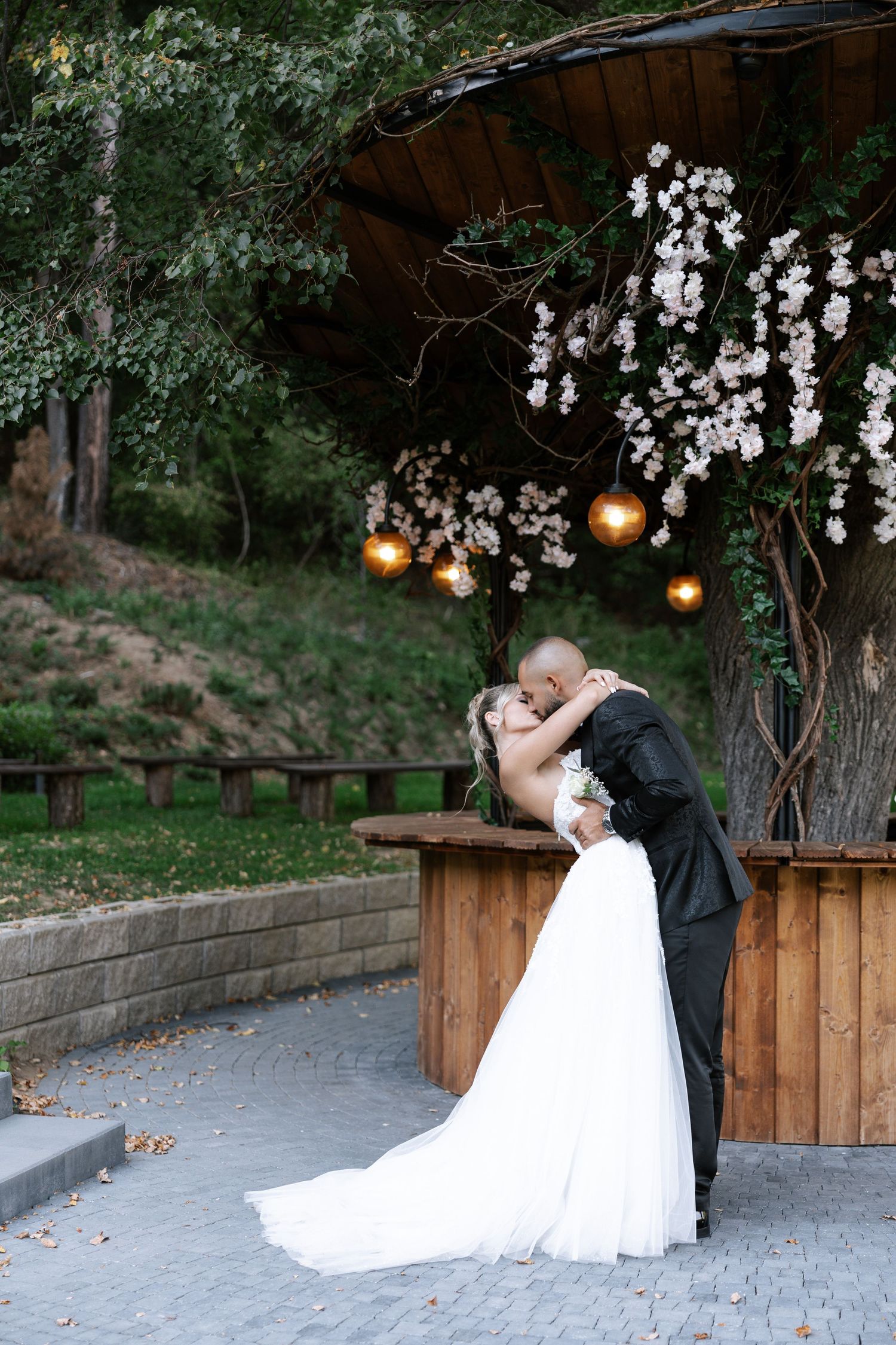 Romantic outdoor wedding scene with hanging lights and wooden fence creating an intimate garden atmosphere.