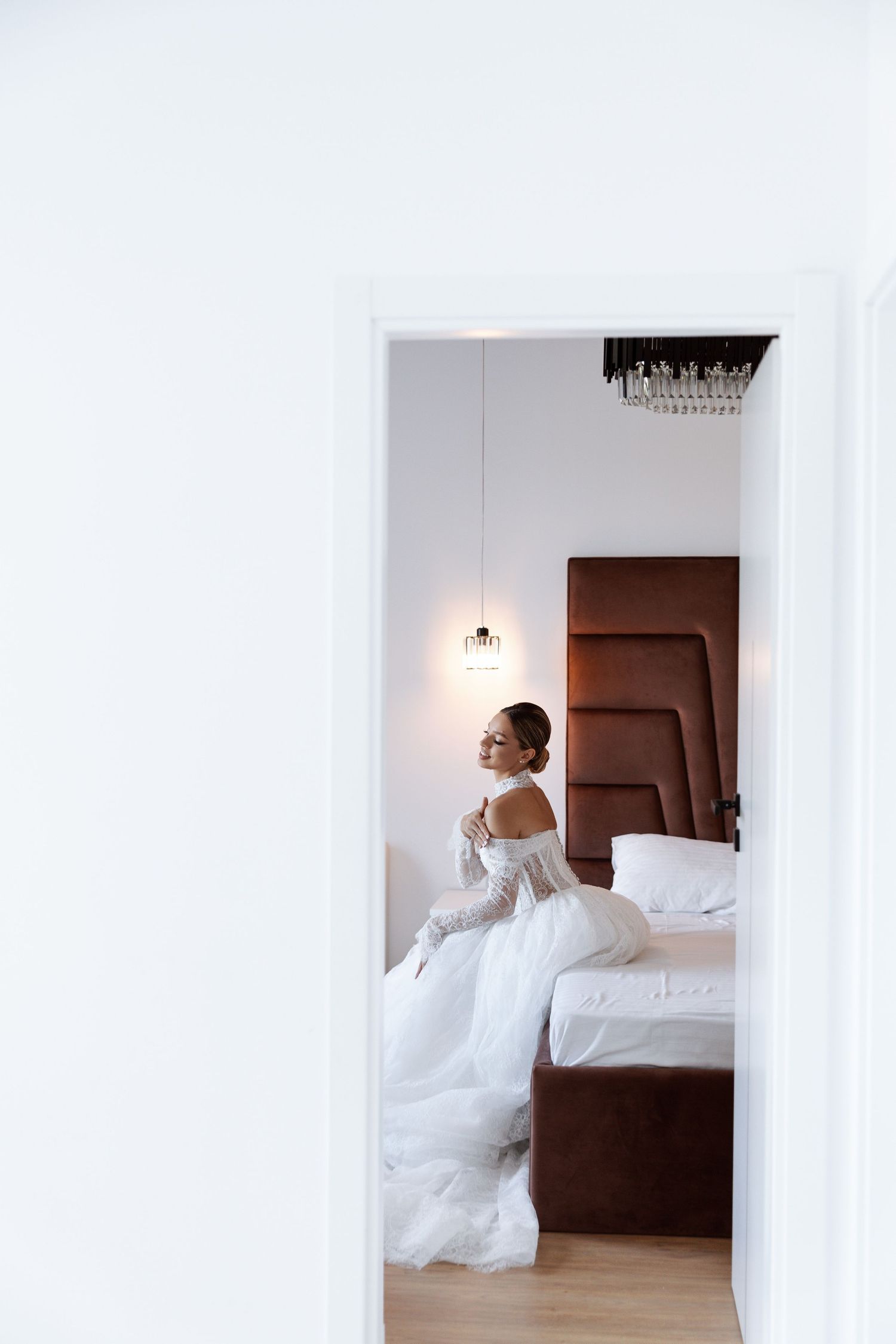 Artistic bridal portraits in a white modern bedroom with soft lighting.
