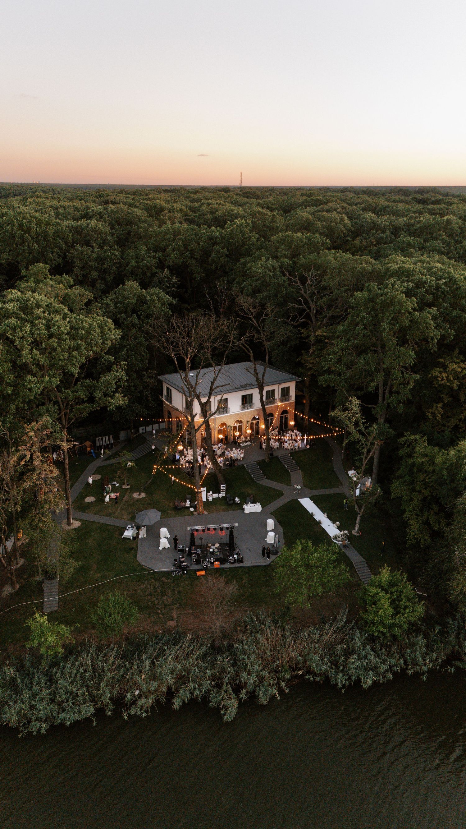 Aerial view of a wedding venue surrounded by trees at sunset.
