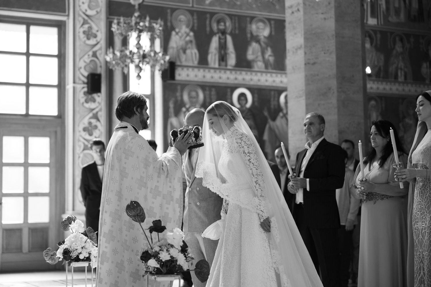 A bride and groom stand at the altar during an Orthodox church wedding ceremony with religious icons in the background.
