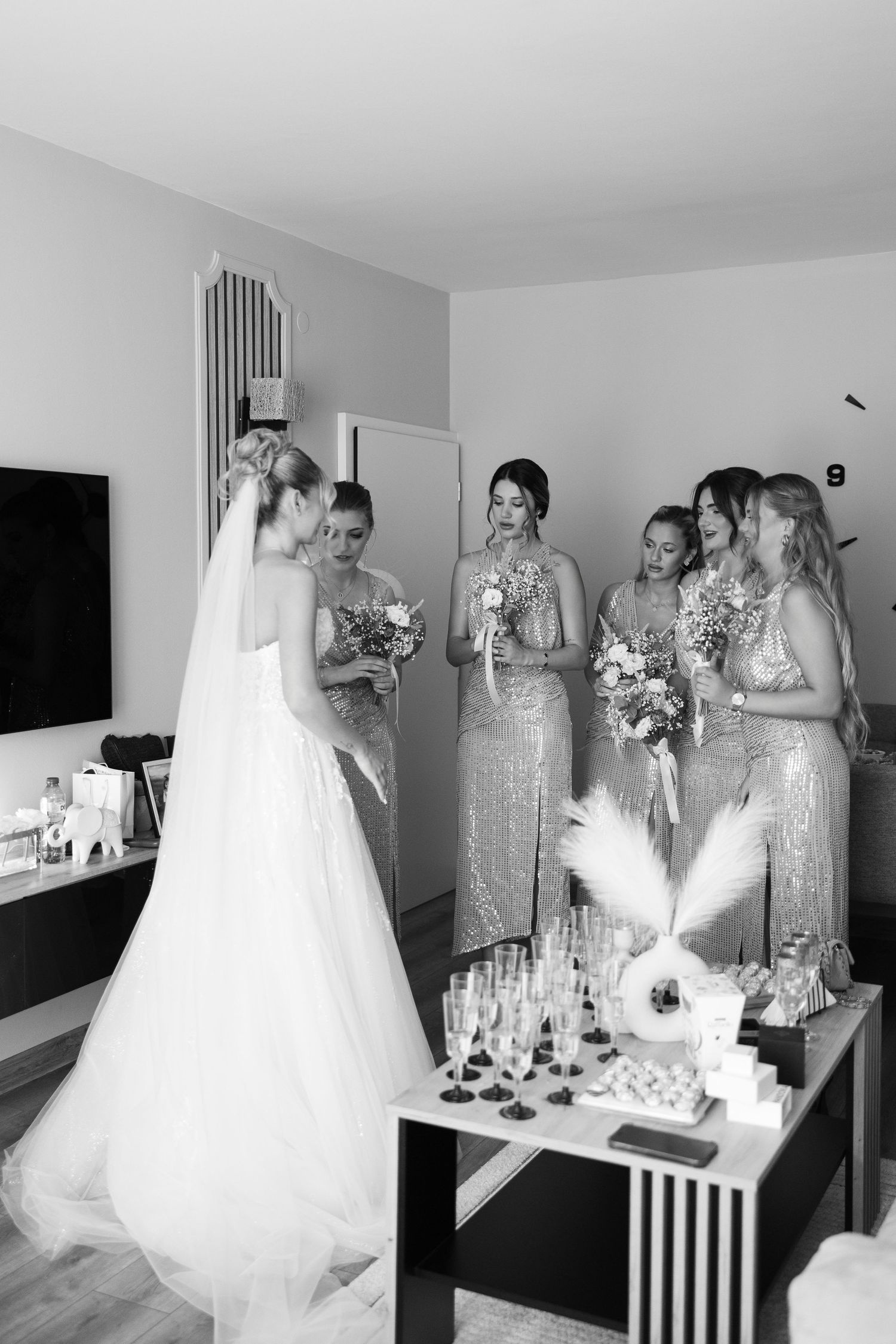 A series of black and white wedding preparation photos showing bridesmaids in sparkly dresses helping with final touches.