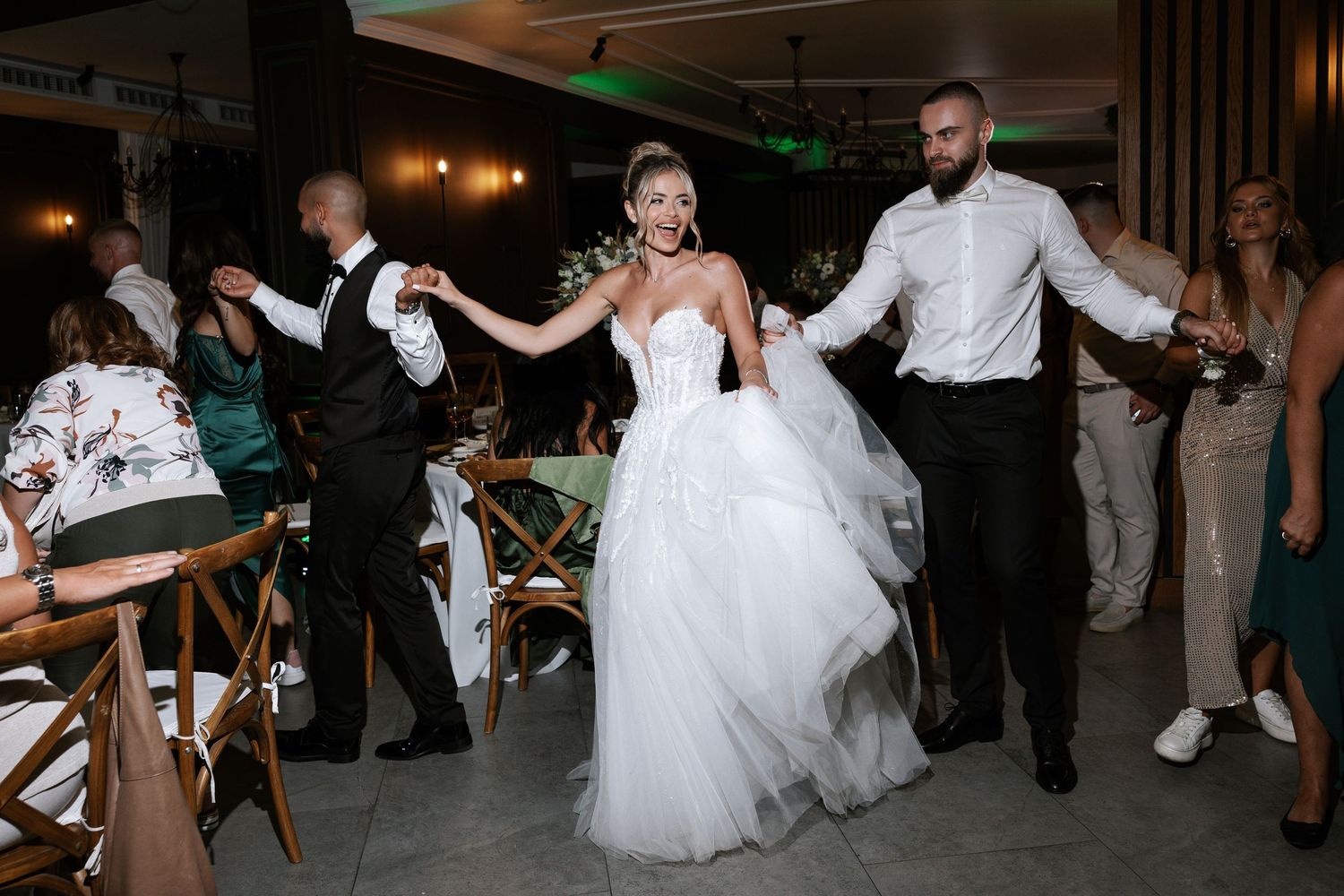 Wedding party dances and celebrates on the dance floor at an elegant indoor reception venue.