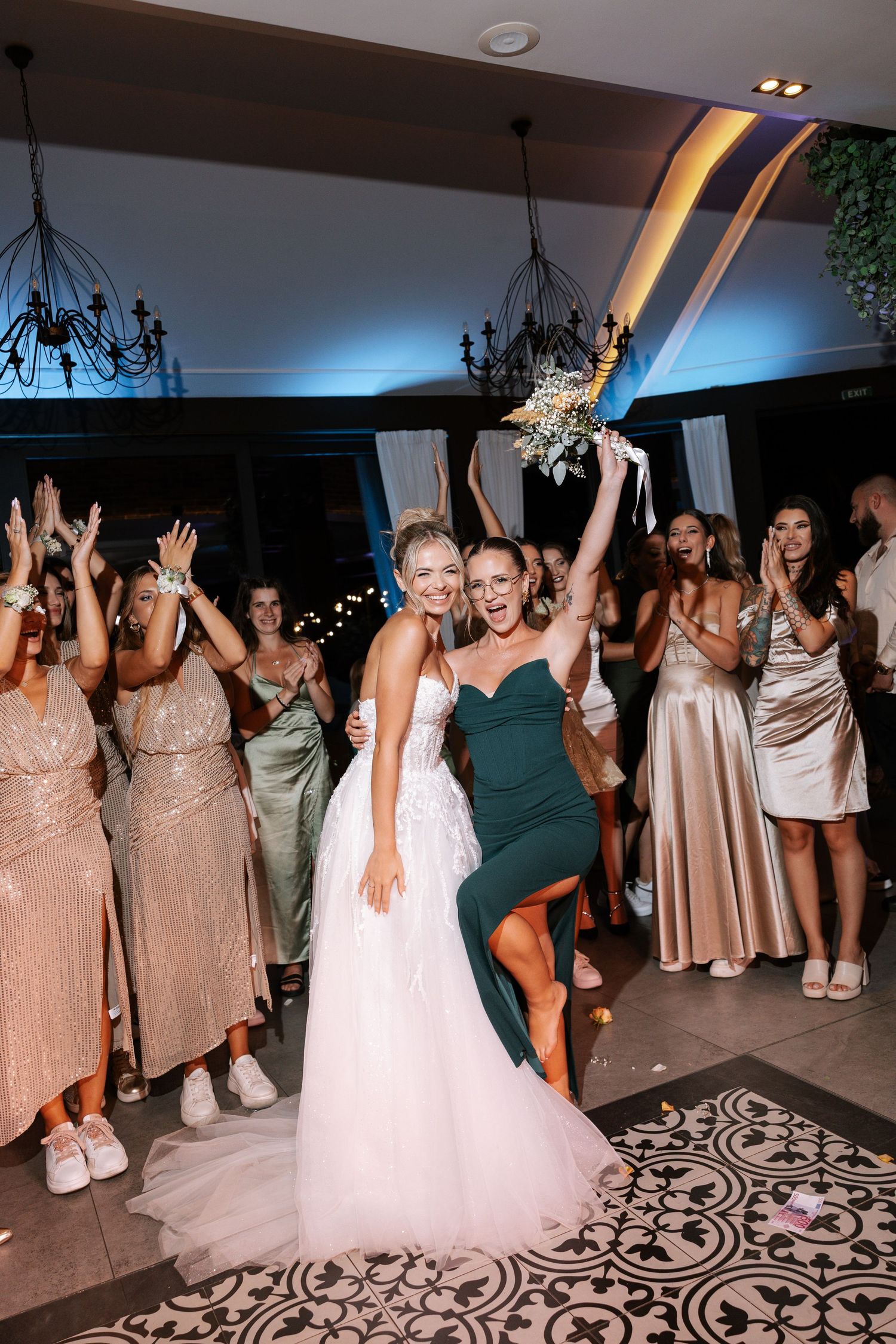 Wedding party dancing and celebrating on an ornate patterned dance floor at an indoor reception venue.