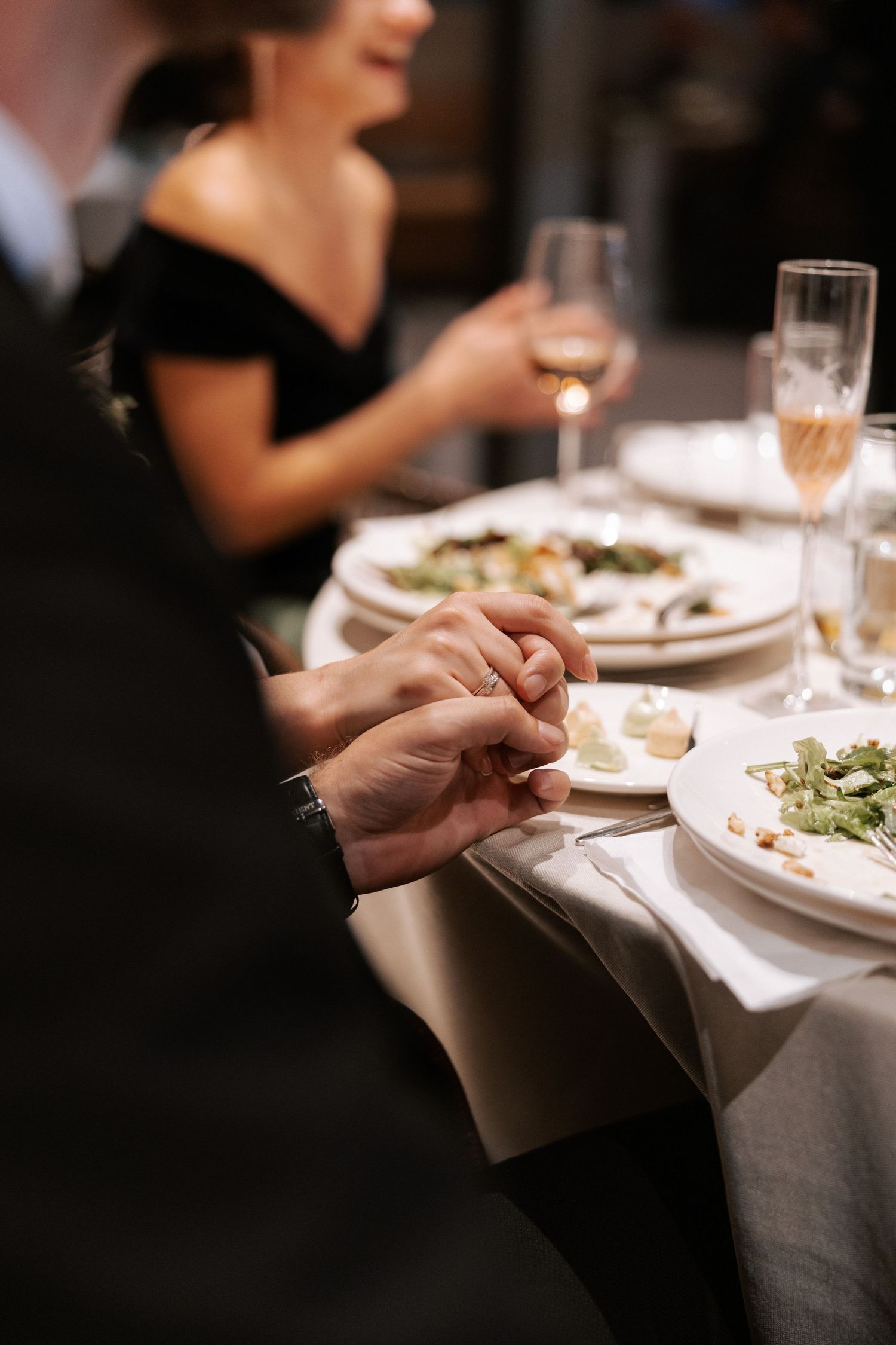 Intimate dinner setting with wine glasses and formal place settings at an elegant reception.